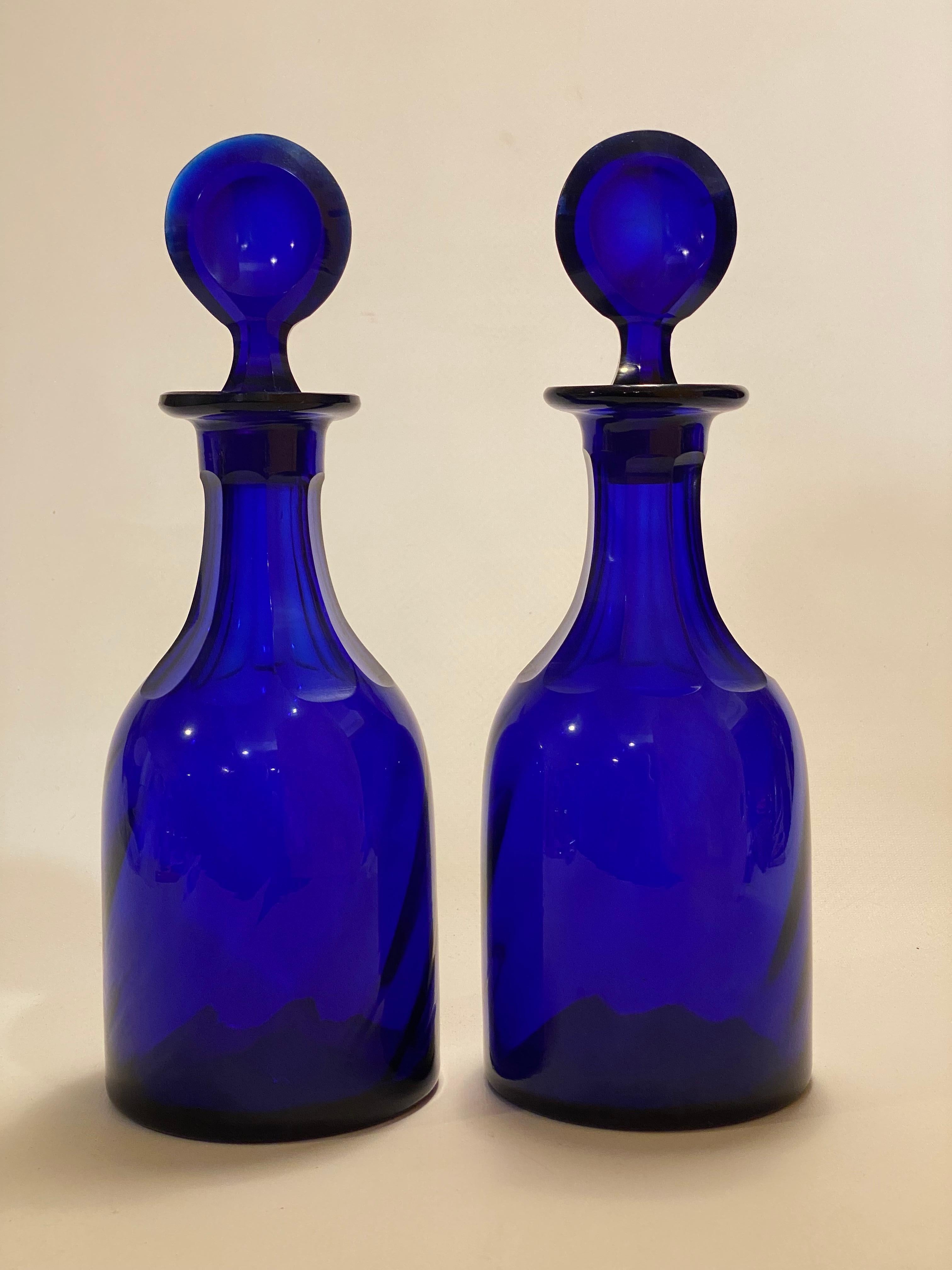 A pair of fantastic carved and polished cobalt glass bottles with stoppers. Beautiful deep deep blue. Polished pontils. The blown bottles have faceted and polished necks and the stoppers have a polished concave design. The pair clearly needs to be