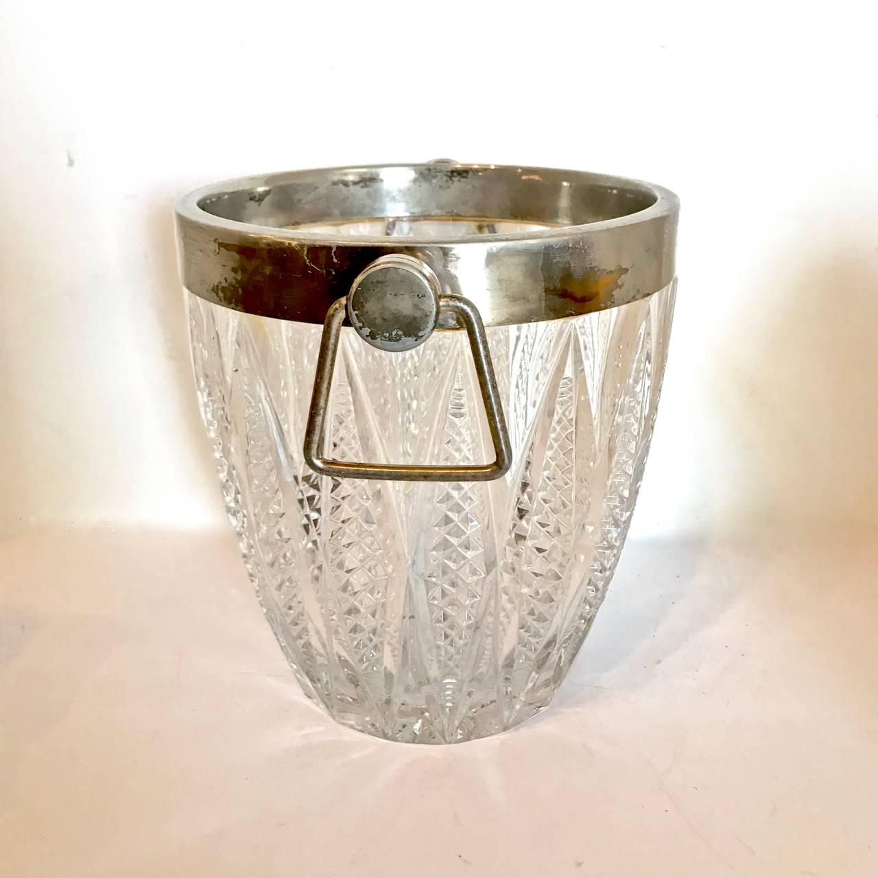 This is a classic 20th century cut crystal and silver plate ice bucket that dates to circa 1950-1960. The bucket is in overall very good condition. There is normal patination to the silver plate rim.