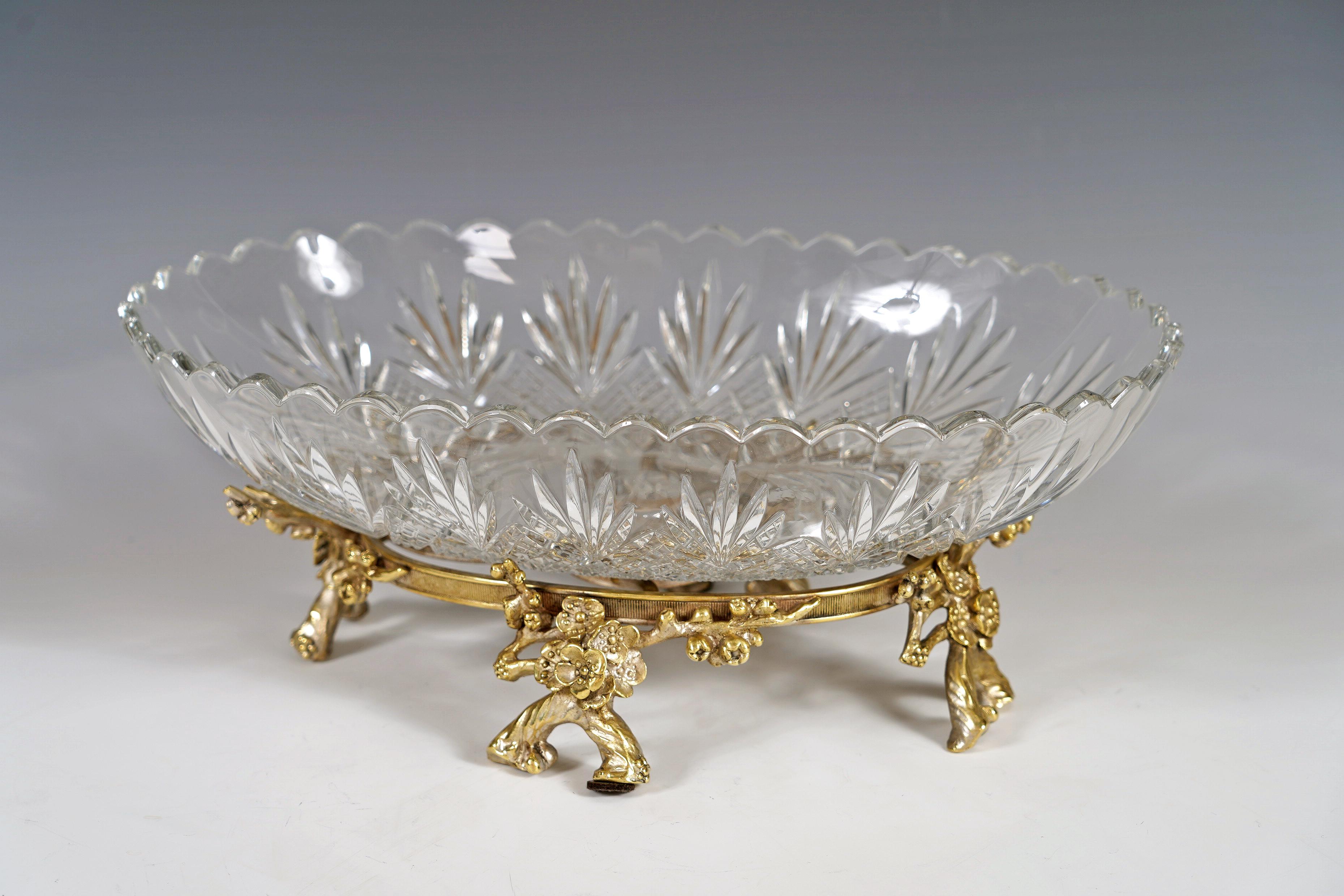 Elegant centre de table ovale en cristal taillé, décoré de palmettes stylisées sur fond de quadrillage, reposant sur une monture en bronze à patine argentée représentant des branches fleuries.

Biographie :
La célèbre cristallerie de Baccarat, dont