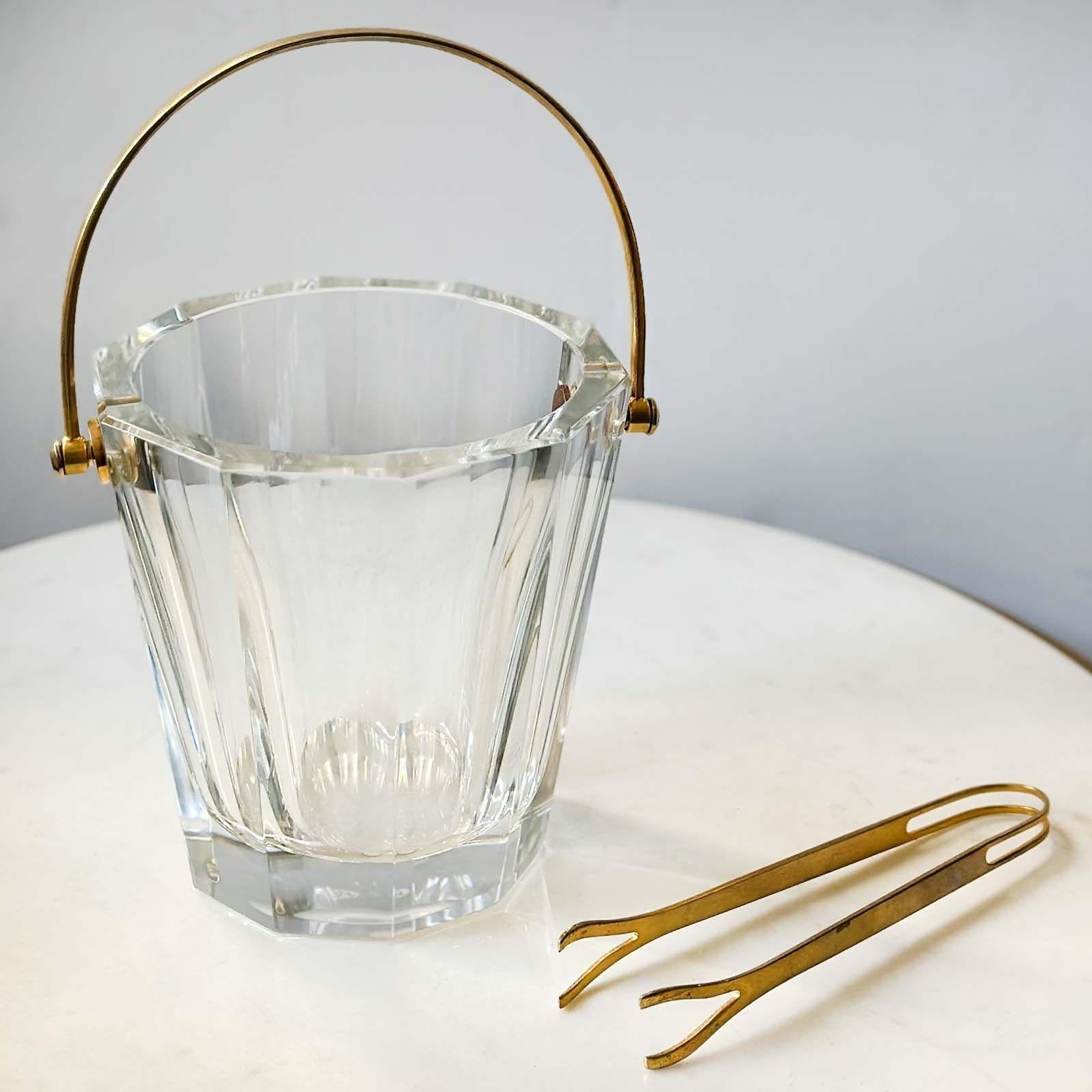 Elegant ice bucket made of rich cut crystal and a gold-plated metal handle by Baccarat, France; followed by a matching ice tong. Made in the 20th Century. The makers mark is etched on the base of the piece.
Dimensions:
9.5