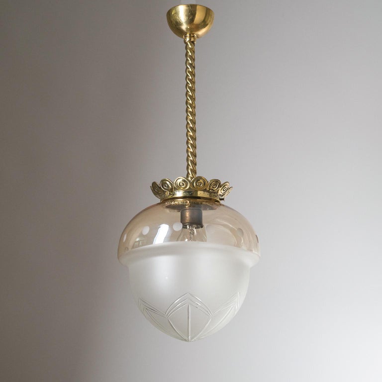 Rare Art Deco ceiling light from the 1930-1940s. Intricately detailed brass hardware and a rare acorn-shaped blown glass diffuser, which has a satin finish on the bottom with cut decorations and an iridescent clear upper half. One original brass E27