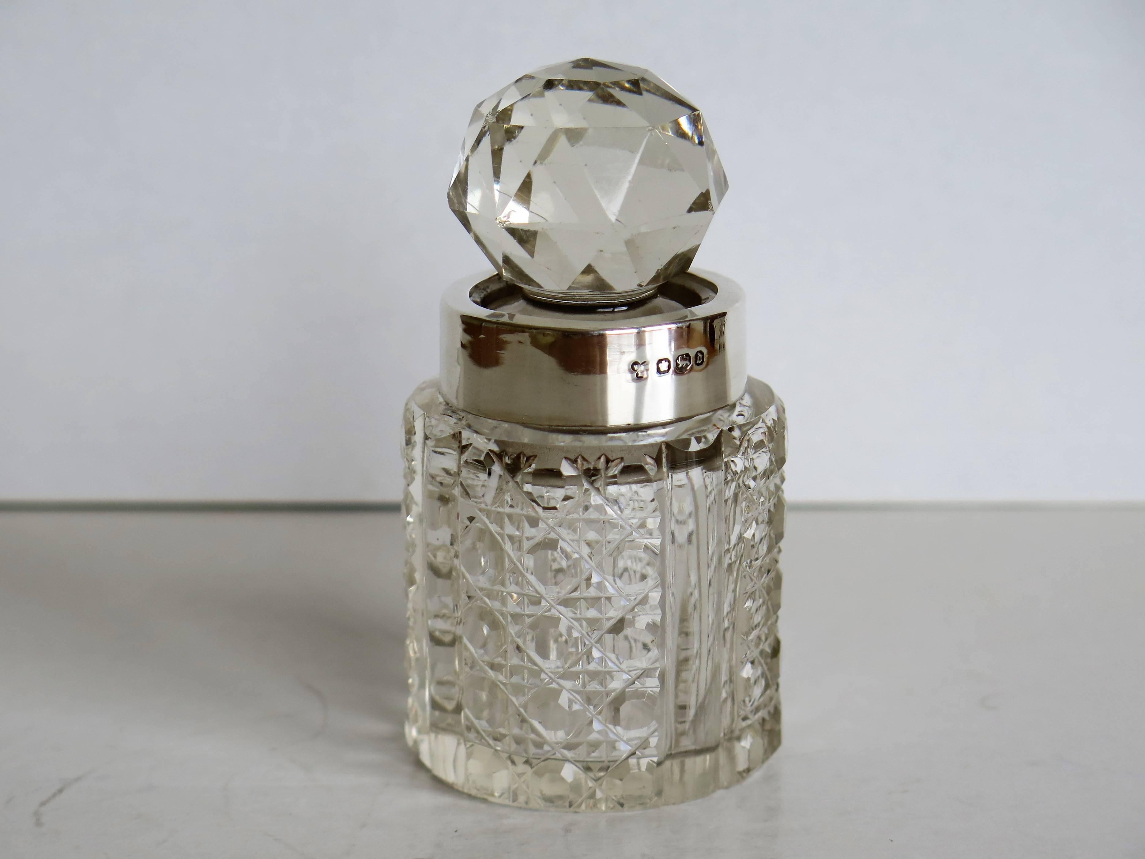 This is an attractive Victorian cut glass or crystal perfume bottle with a sterling silver neck ring made by William Harrison of Sheffield, England in 1896. 

The bottle has a slightly oval shape with four vertical flutes and decorative diamond cut