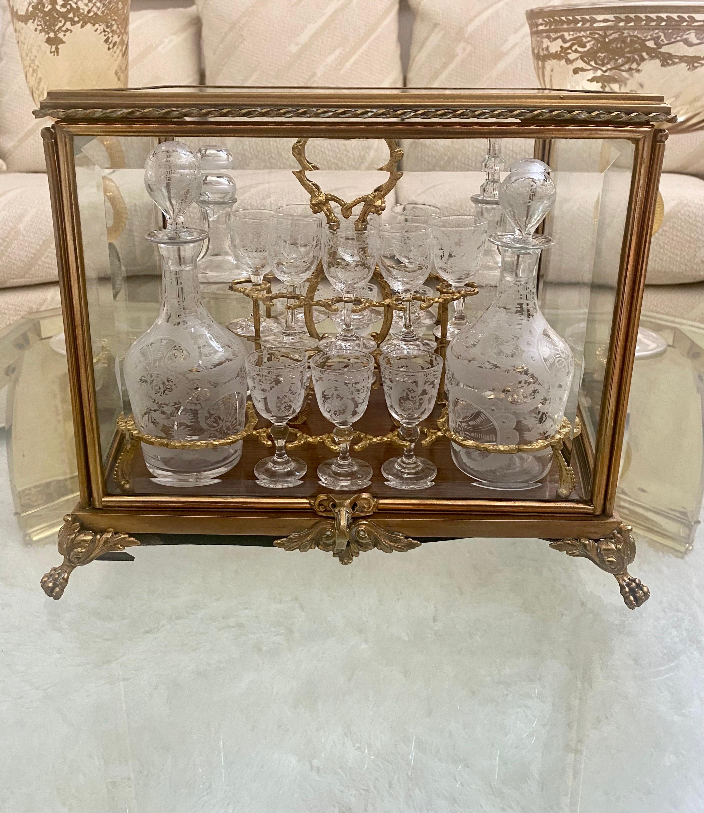 A delightfully designed gilt bronze and etched crystal glass set, in the style of Baccarat. The set includes fourteen glasses and four decanters with etched embellishments. The set is placed on a lift out  custom gilt  tray inside of a beveled