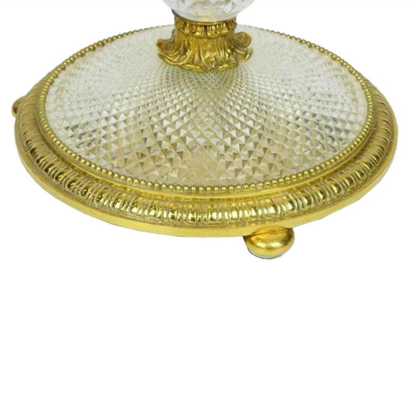 An occasional round table having a mirrored top with a decorated gilt border. The top sits on a shaped wasted column made of one piece of heavily faceted and polished crystal. The column joins a circular cut crystal base also having a gilded bronze
