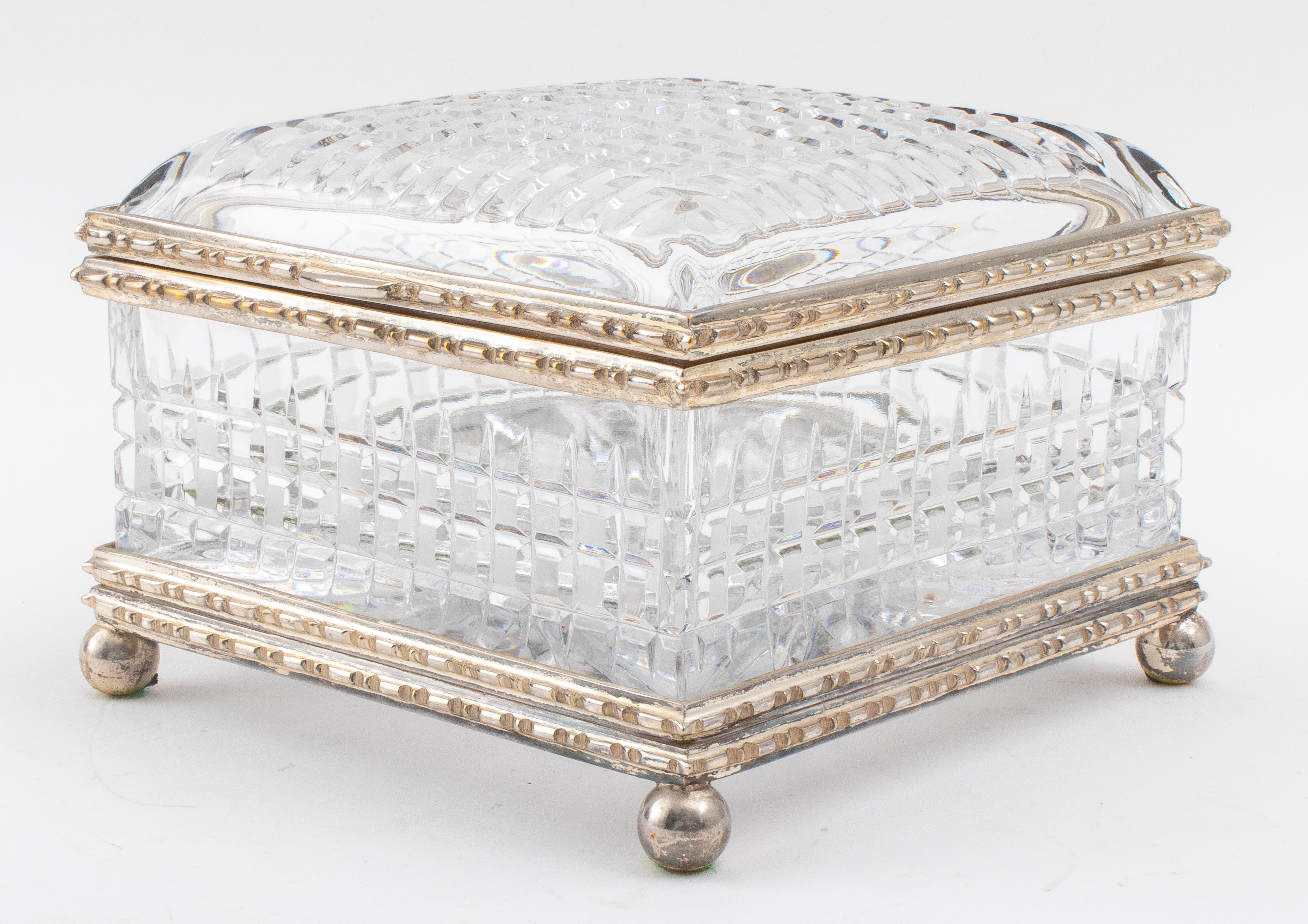 Cut glass and silvered metal mounted casket, square, the square cut and faceted domed top with a boldly cast hinged mount, above a similarly cut and mounted base above spherical feet. 
Size: 5.5