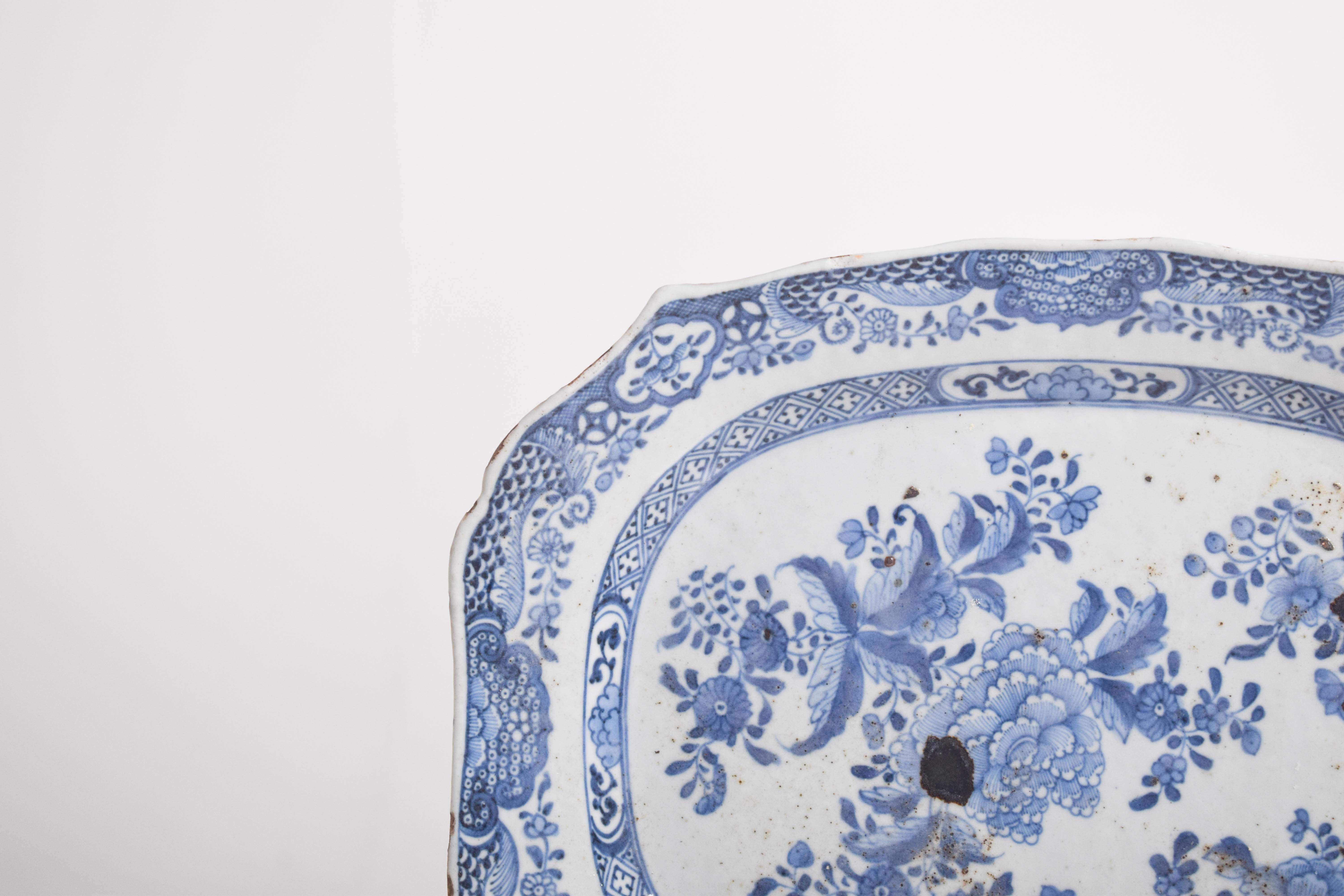 This cut-out serving dish, crafted from Chinese porcelain during the Qing dynasty, Qianlong period, is a fine example of export porcelain. The dish features a classic blue and white design, with intricate floral motifs delicately painted across the