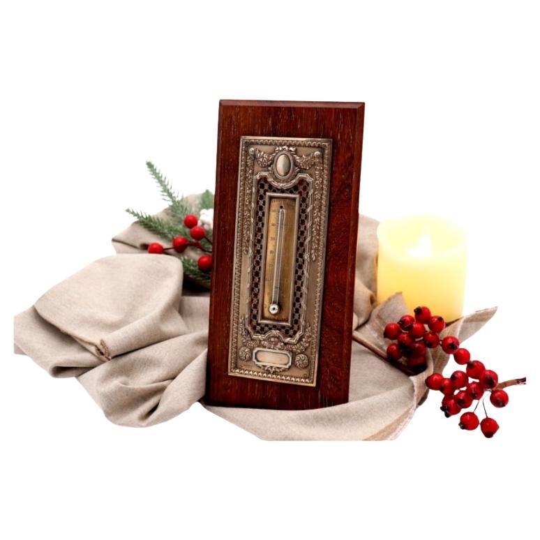 Cut-out silver thermometer with monogram card 
wooden stand