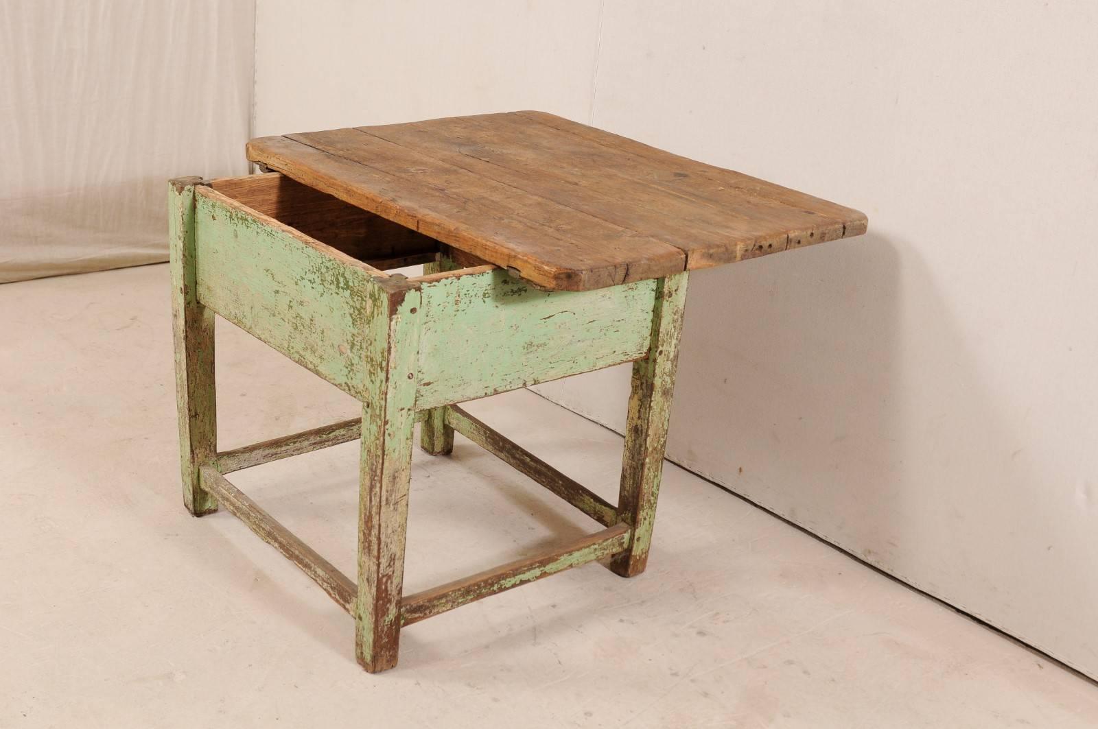 A 19th century European table with sliding top feature. This antique European table is rustic and inviting with its beautifully aged, natural wood top, a nice contrast to the base which has remnants of its original old green paint throughout. The