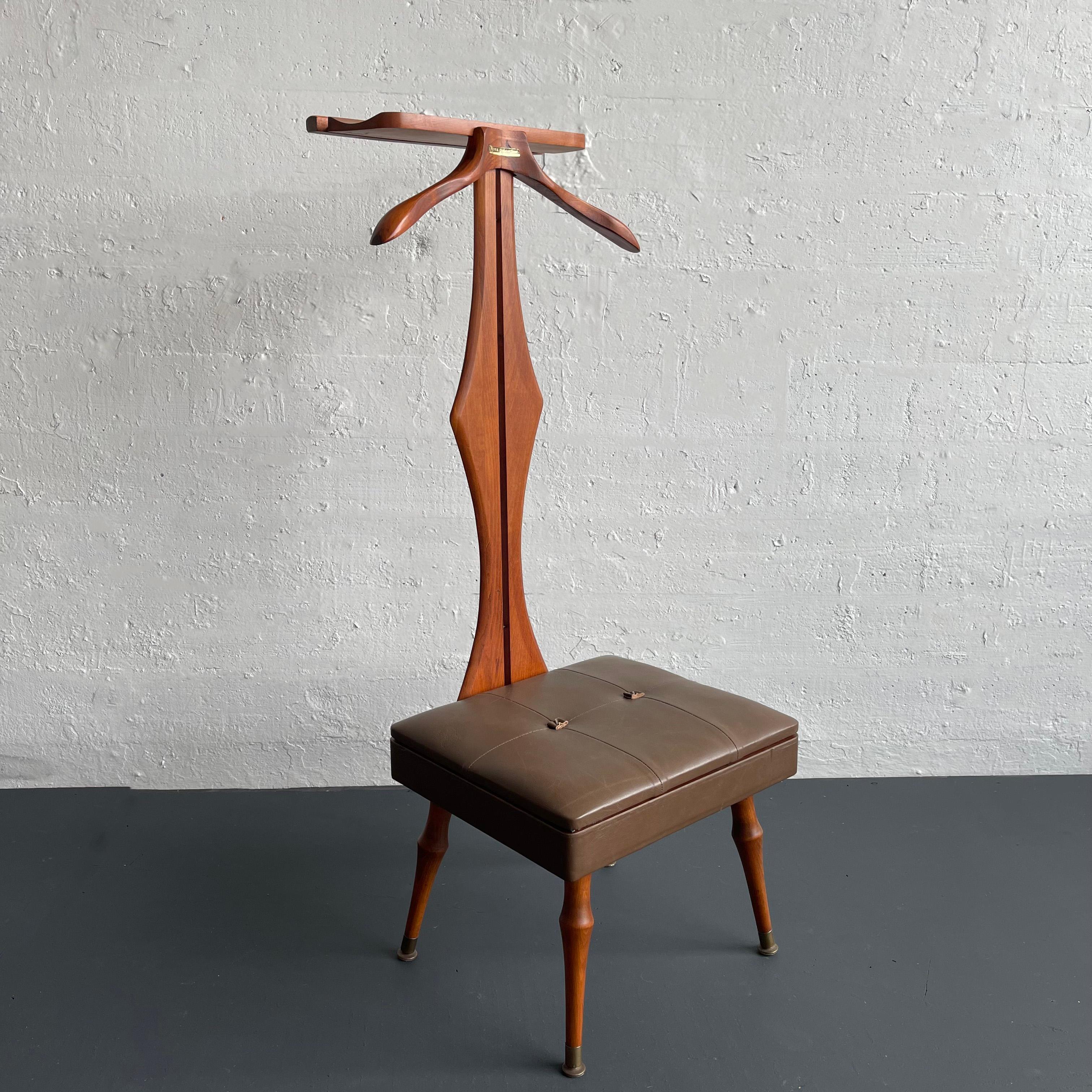 Mid-century modern valet chair with a sculpted walnut stem holds features a pants hanger, jacket hanger and a generous tray for a watch, cuff links, tie clips, and jewelry. The newly upholstered, tie-tufted leather seat opens to reveal a blue felt
