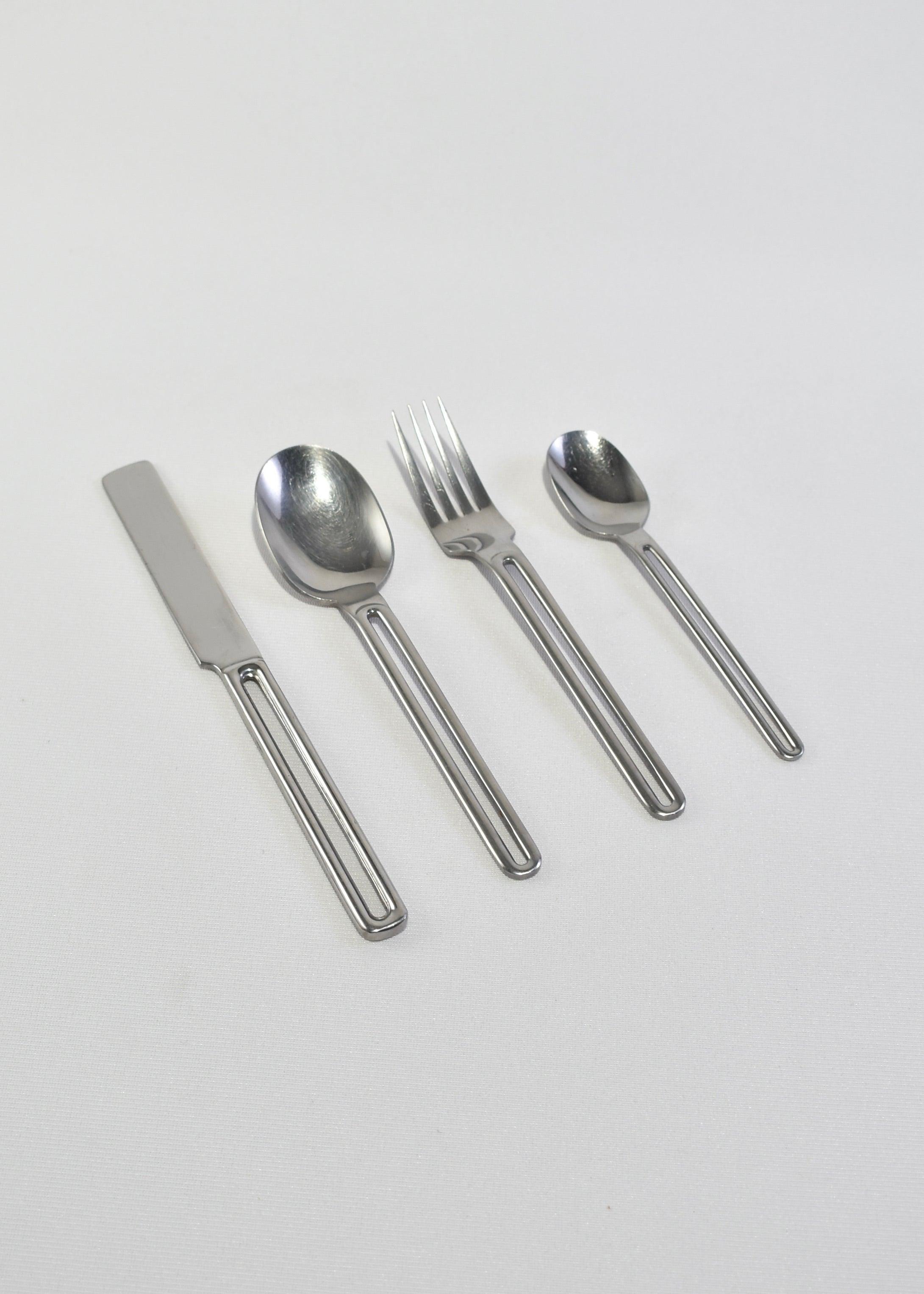 Rare, stainless steel four-piece flatware set with cutout handle. Made in Japan.

Purchase includes one set of four pieces, one set available.

Dimensions: 
Knife: 9 in (22.86 cm) long 
Spoon: 7.5 in (19.05 cm) long
Fork: 7.5 (19.05 cm)