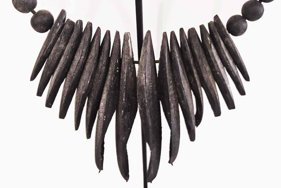 A decorative necklace from Bali, Indonesia, made of black cuttlefish bones. A singular piece of Balinese handcraft that will add an exotic touch to any eclectic decor. Mounted on a black metal stand for maximum display effect.
 