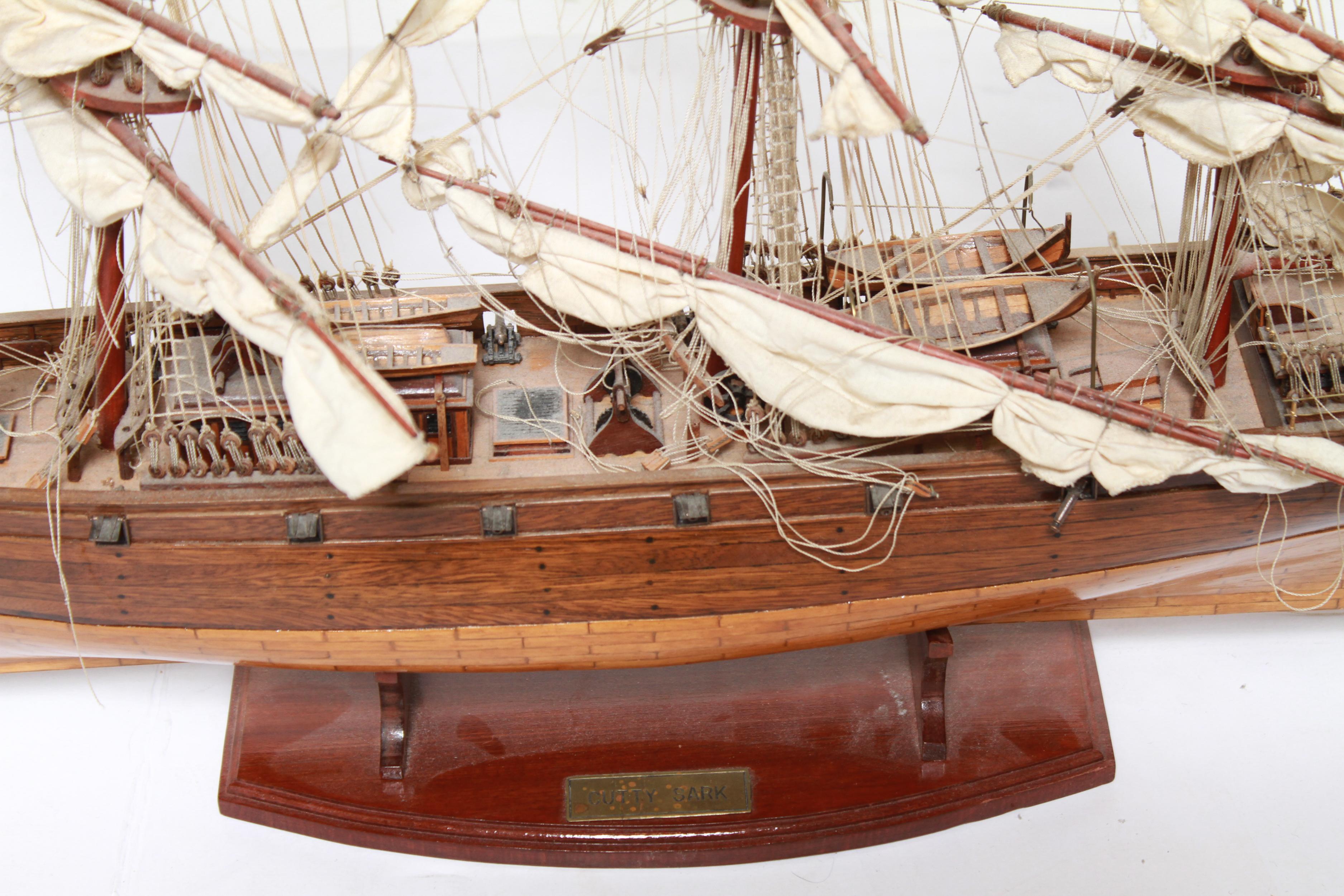 'Cutty Sark' china clipper three-mast tall scale model in teak, mahogany, ebony and other woods, with linen sails and cotton thread rigging, on stand with brass name plate. Lacking two cannons on one side. Needs re-rigging.
