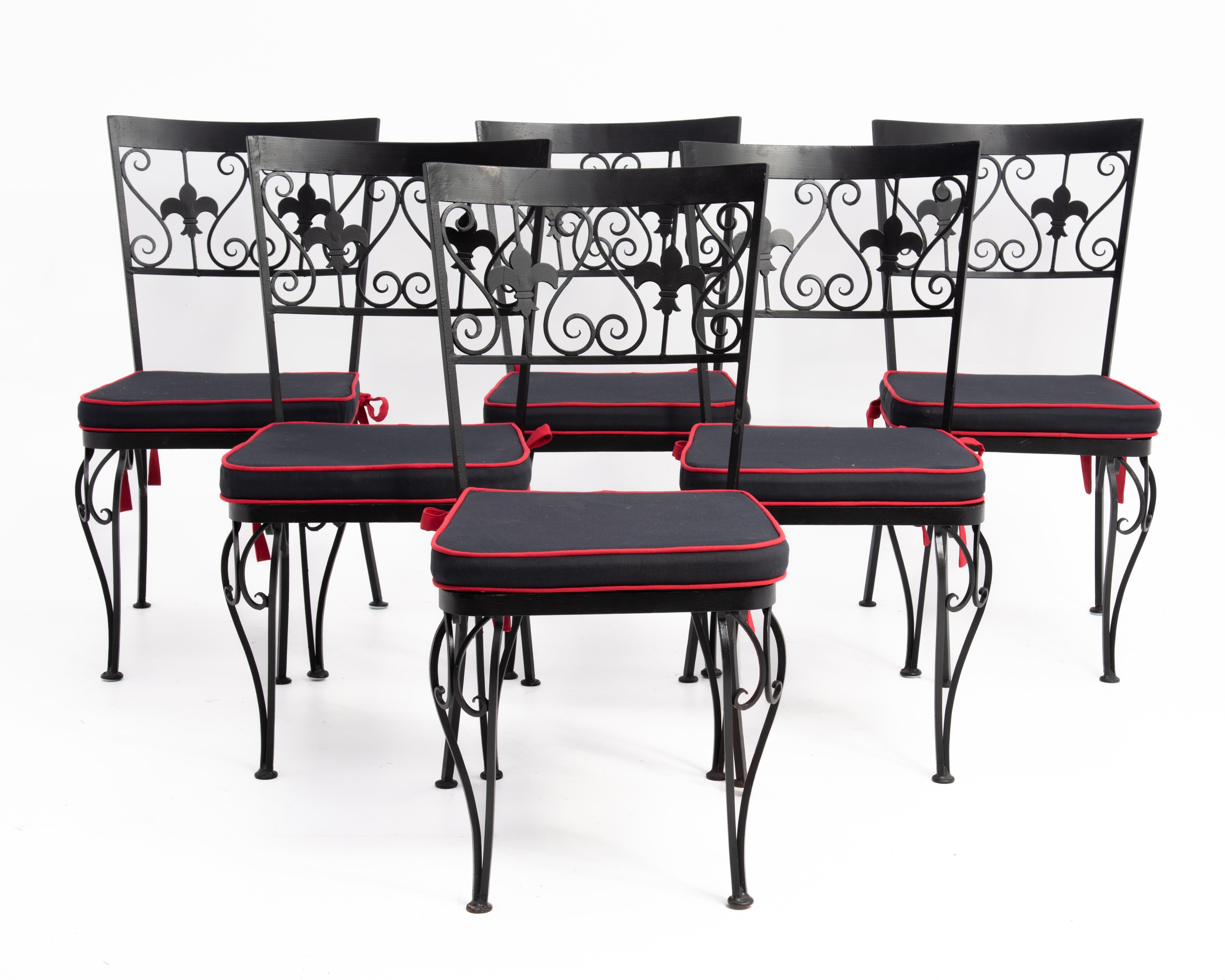 A stylish set of six wrought iron dining chairs with mesh seats, hand tied seat cushions and Fleur-De-Lis decoration. Custom made in America for a New York City Restaurant in the 1960s. 
The seat height without the cushion is 15.75