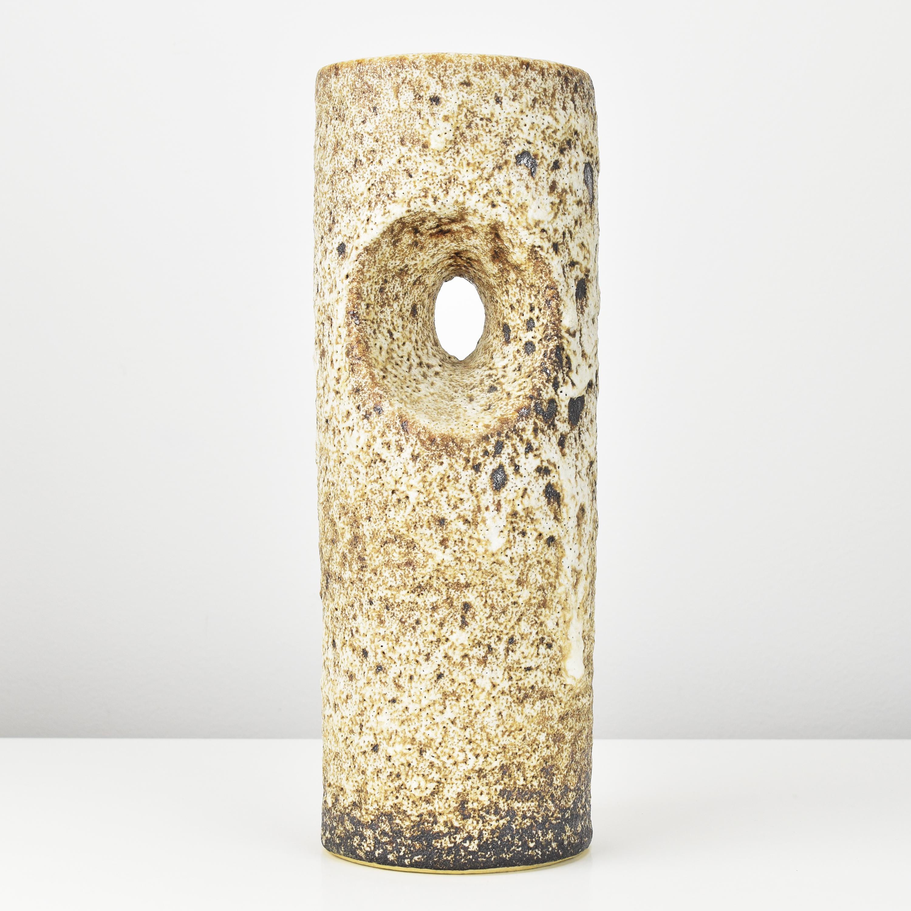 This Mid Century ceramic vase is a stunning piece from the 1960s, featuring a distinctive beige-brown Fat Lava glaze. Its most notable feature is the unique opening in the body, which not only sets it apart as a true work of art but also serves as a