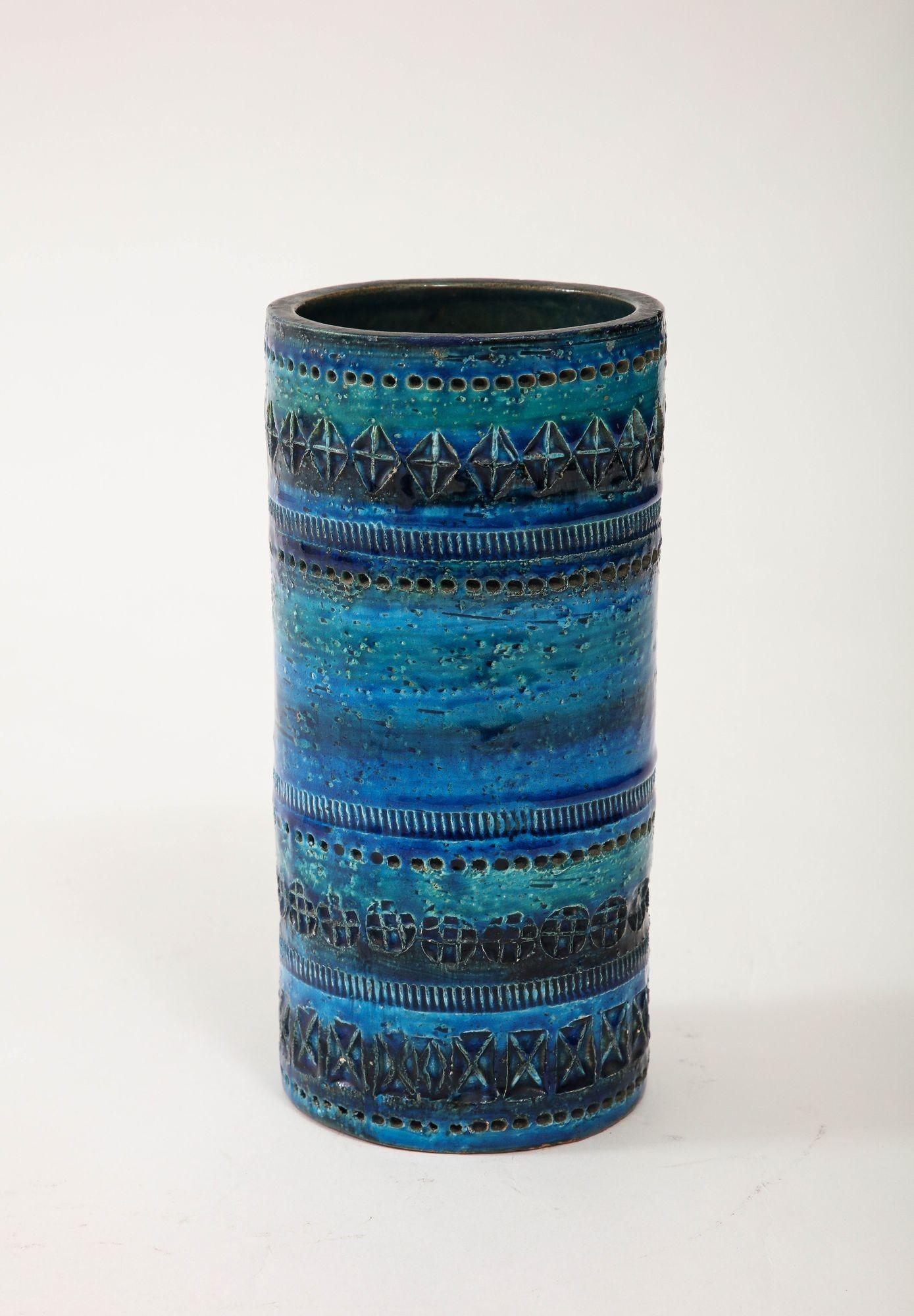 This Bitossi Ceramic Cylindrical Vase, crafted circa 1960, is an exquisite example of Italian ceramic artistry. Drenched in the alluring 'Rimini blue' glaze, it exudes a timeless charm. The vase's simple yet elegant form serves as a canvas for
