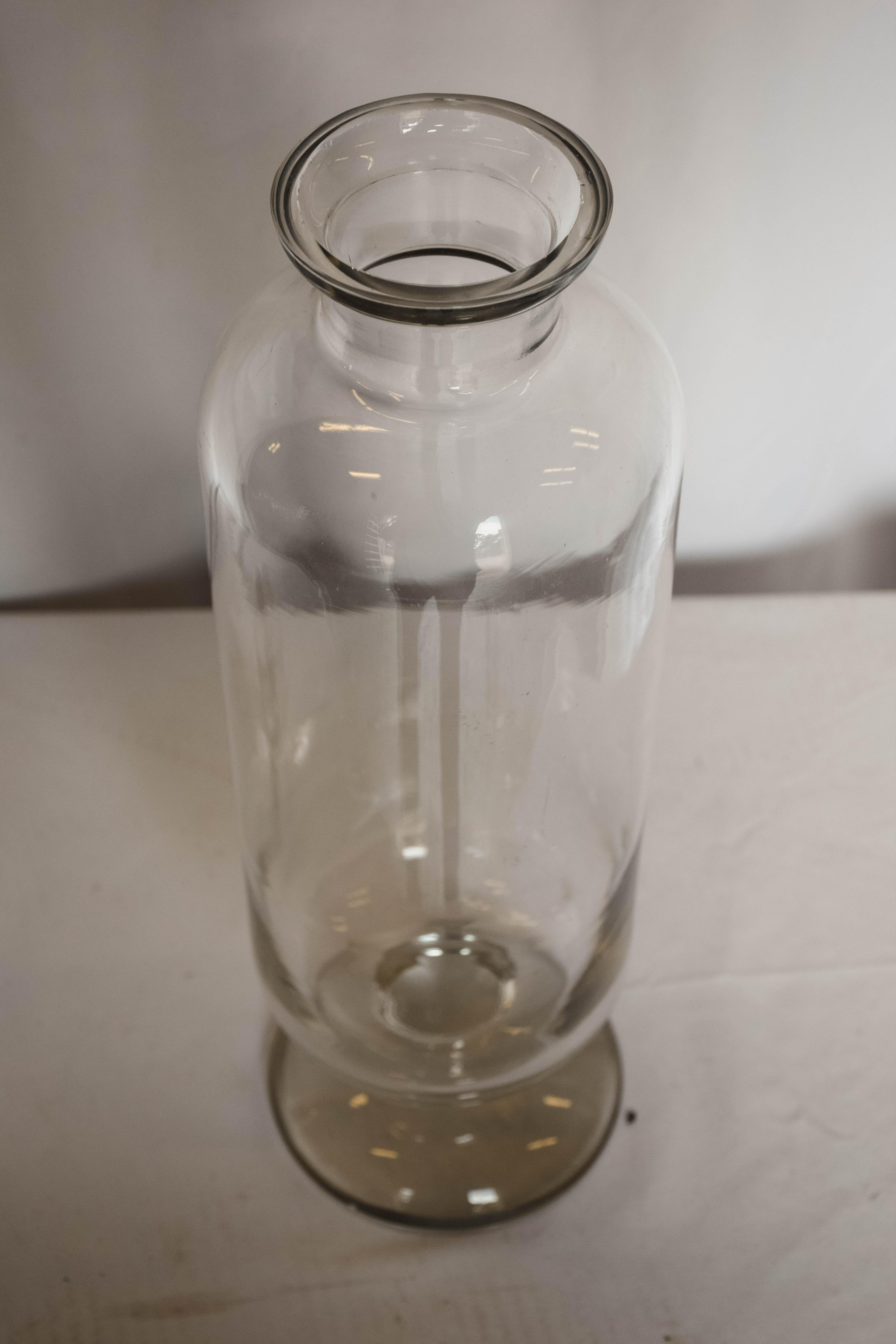 A cylindrical glass candy jar, with a lid and rounded bottom. Top is a linear cut bevel in the shape of a diamond. Truly gorgeous and useful. Use it for cookies and candies in the kitchen or aside a tub with your favorite bath salts.