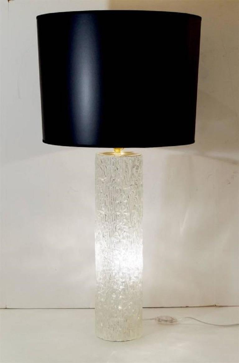 A beautiful cylindrical lamp attributed to Kaiser Leuchten with interior lighting, the exterior having a mottled organic ice glass surface with a refracting interior pattern.
Interior socket takes one E-14 base bulb up to 40 watts. Top socket takes