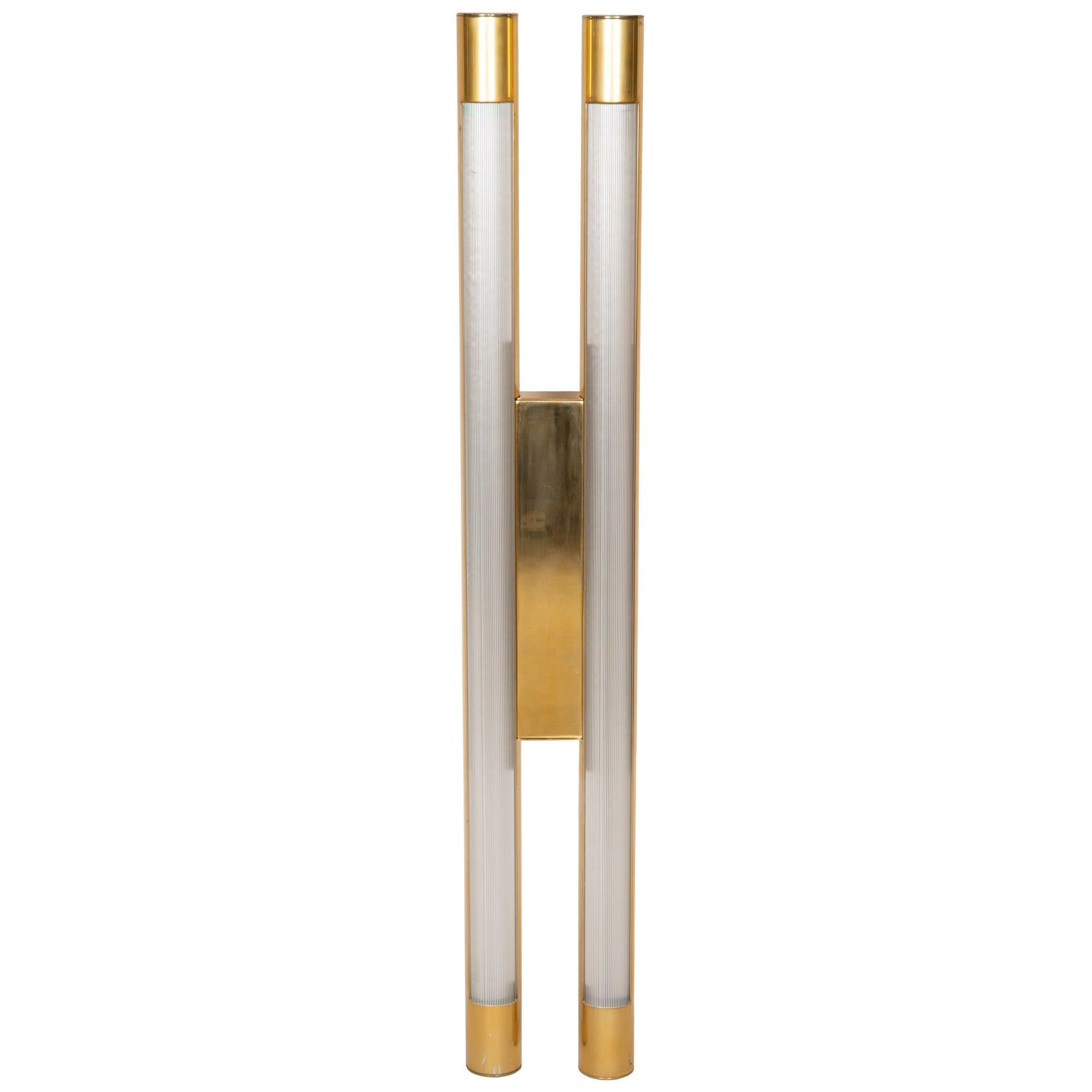 A hanging lamp consisting of two polished cyclindrical sections joined by a rectangular panel. Threaded adapters on the back allow it to be mounted to a wall or ceiling