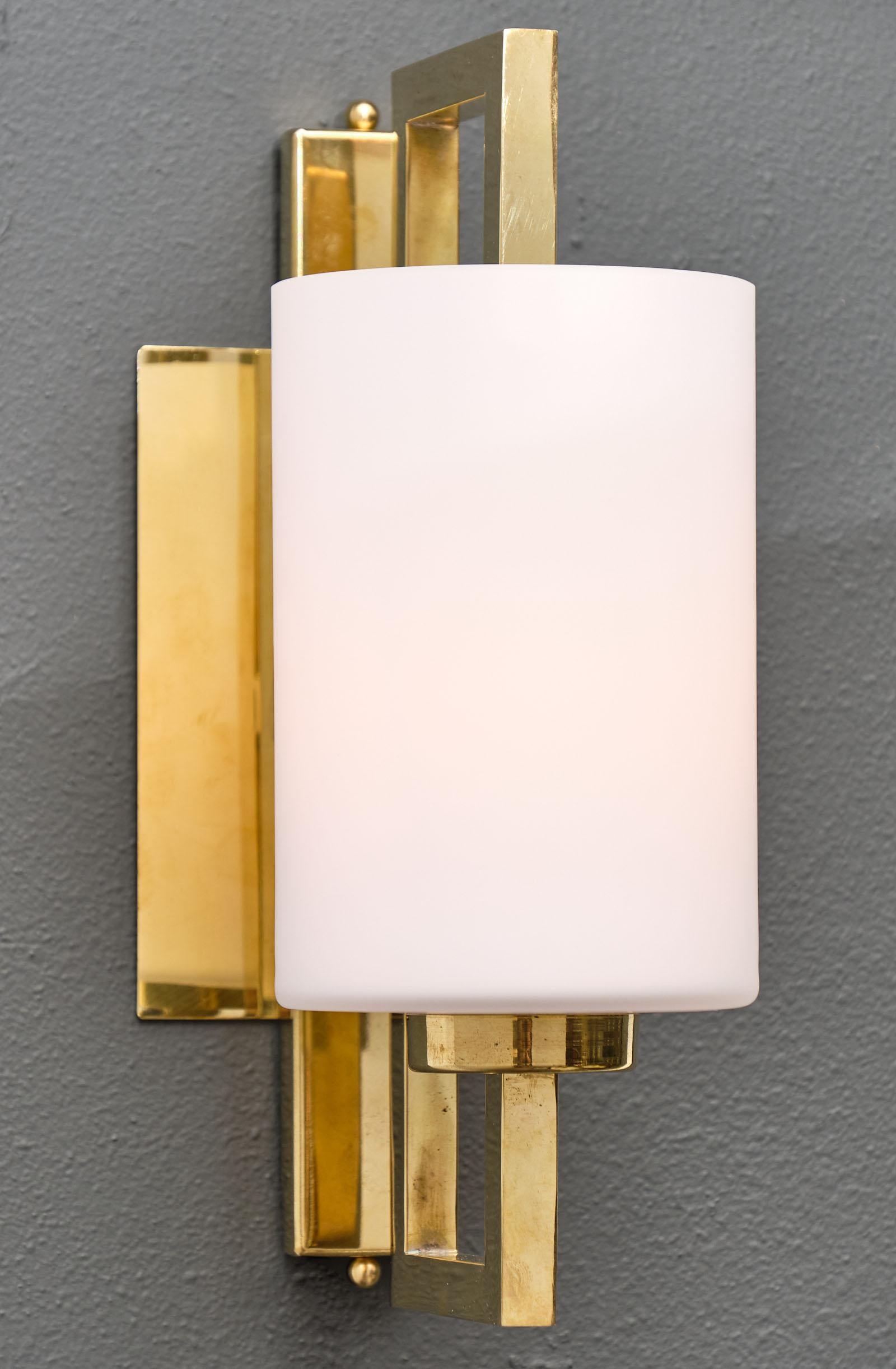 A pair of Murano glass cylindrical sconces featuring a large hand blown frosted cylindrical glass element held in its center by an opened rectangular brass structure. This pair has been newly rewired to US standard.

This pair is a special order