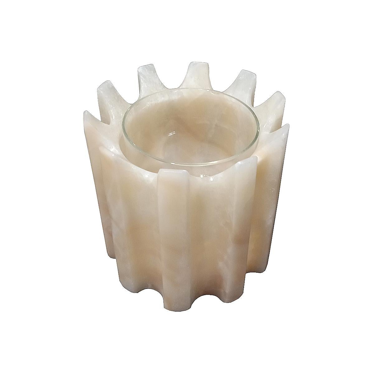 Eine atemberaubende zylindrische Vase mit geschnitzten Rippen, in Creme Farbe Onyx. Er enthält eine dünne Glasvase, die Wasser oder Erde aufnehmen kann. Funktioniert als Übertopf oder als Blumenvase. 
