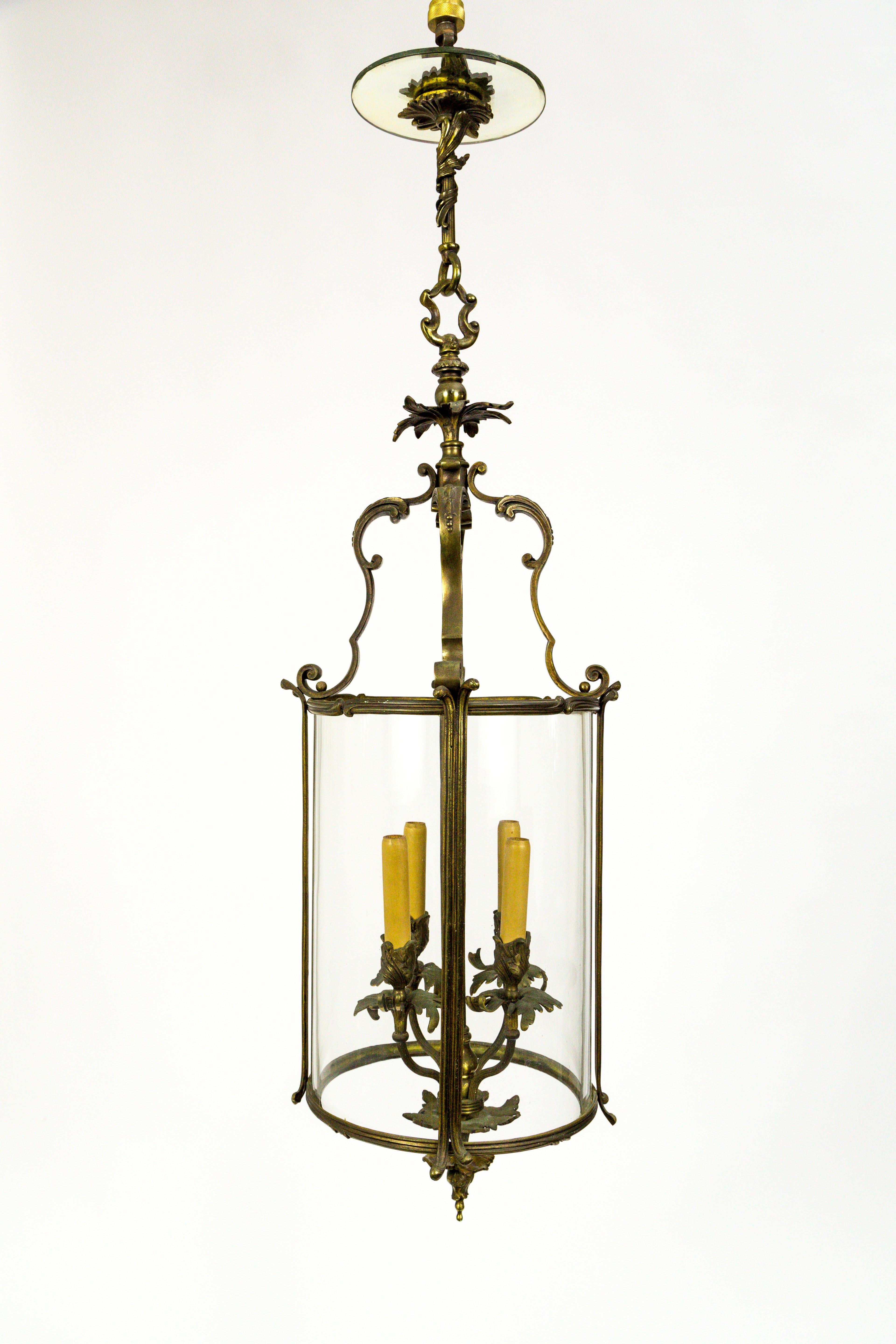 This French Regency style lantern is truly magnificent.
The details and shapes of the body, made of bronze that was formerly gilded, adorn cylindrical, handblown glass. The foliate decorations on the stem, finial, and four-light candelabra cluster,