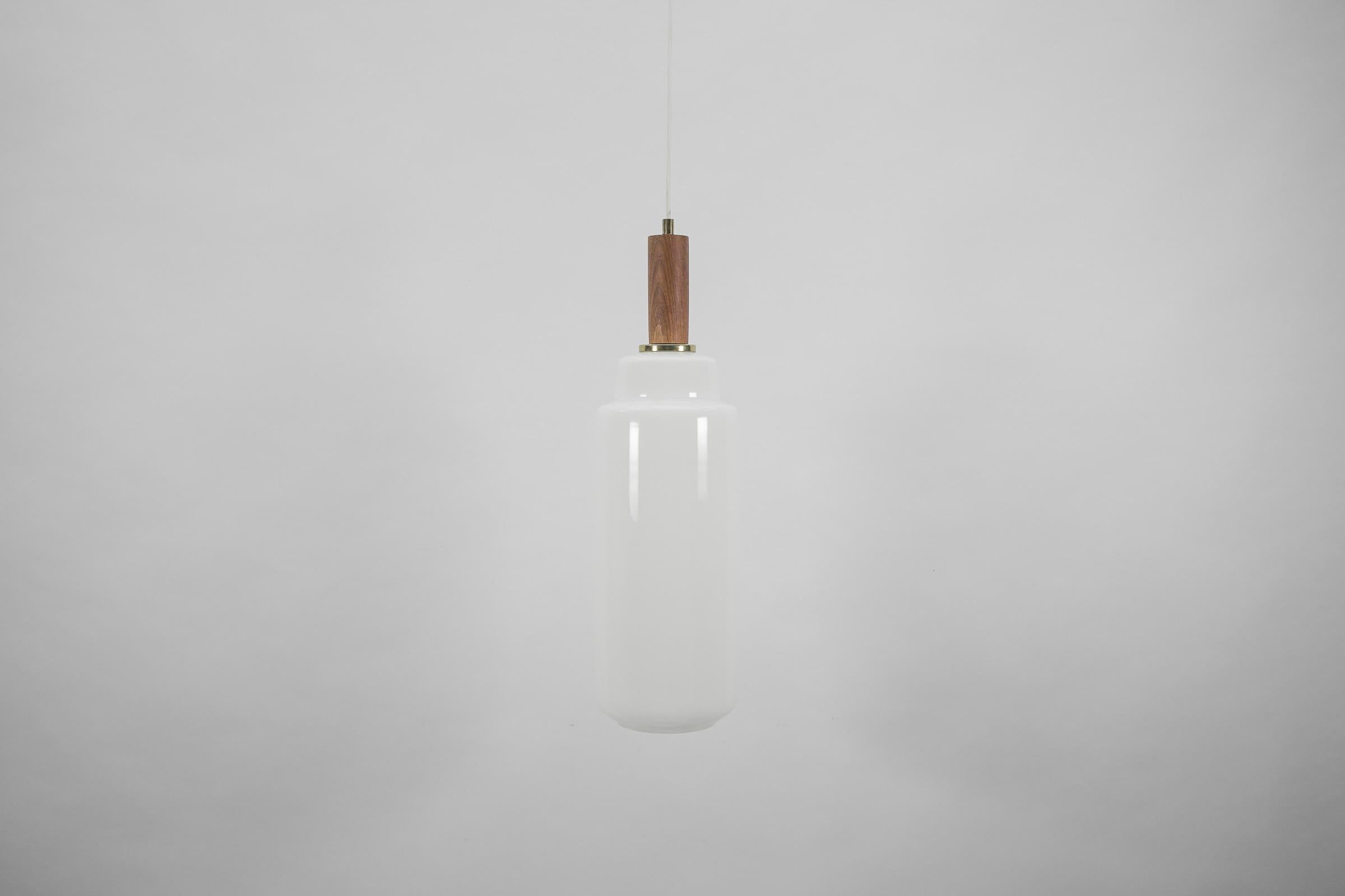 The lamp can be adjusted up from 70 to 120cm height.

Executed in opaline glas, brass and teak wood.

The pendant lamp comes with 1 x E27 / E26 Edison screw fit bulb holder, is wired and in working condition. It runs both on 110/230 Volt. 
Delivery