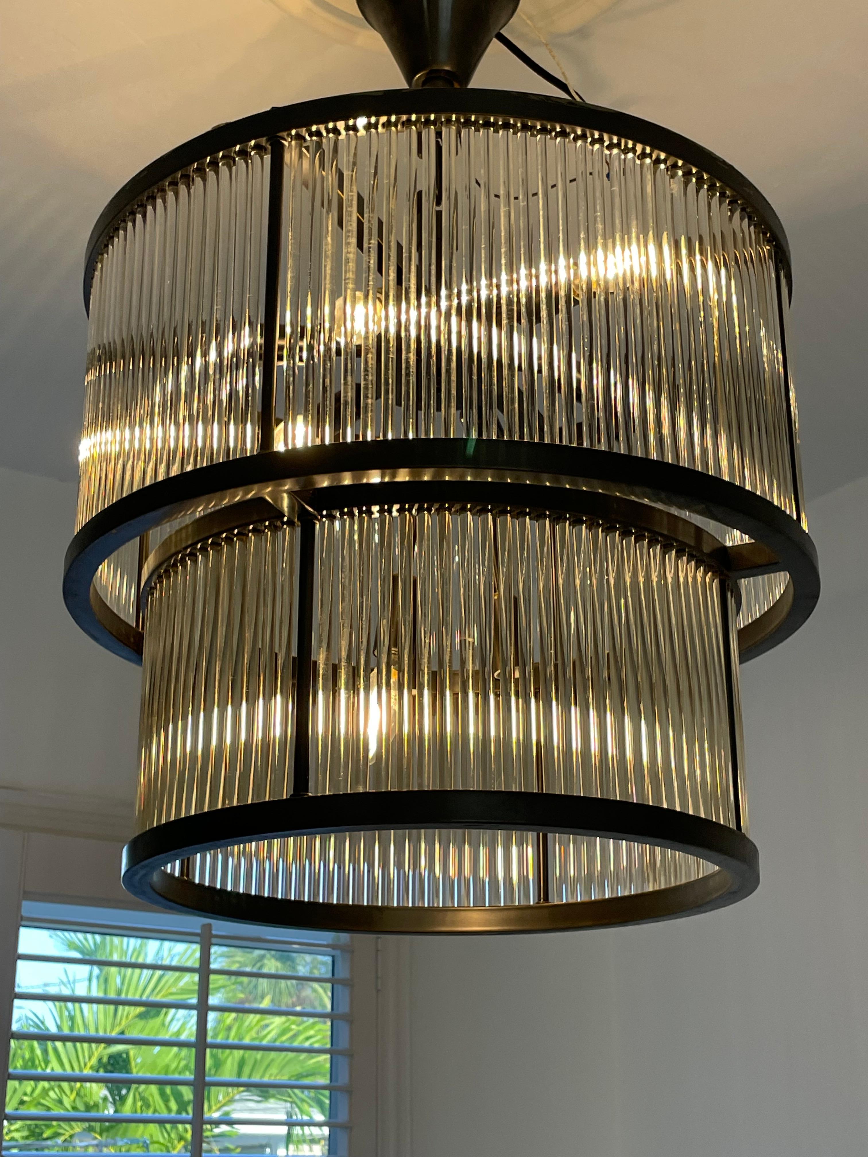 Circular metal chandelier composed of two floors of glass tubes, the light diffuses from the bottom as all around the chandelier through the glass rods and gives a considerable effect to the diffusion of the light.