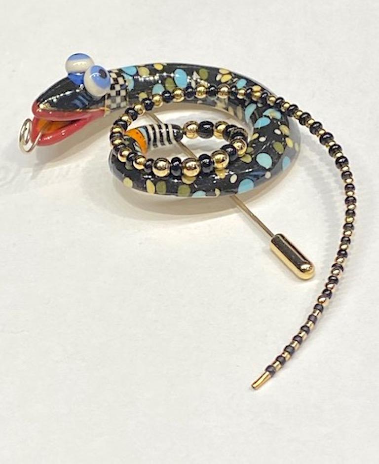 A one of kind hand made snake brooch from the company Jewelry 10. These pieces are highly collected and displayed. The porcelain body is meticulously hand glazed in solid black with light blue, yellow, white and grey polka dots in various sizes. The