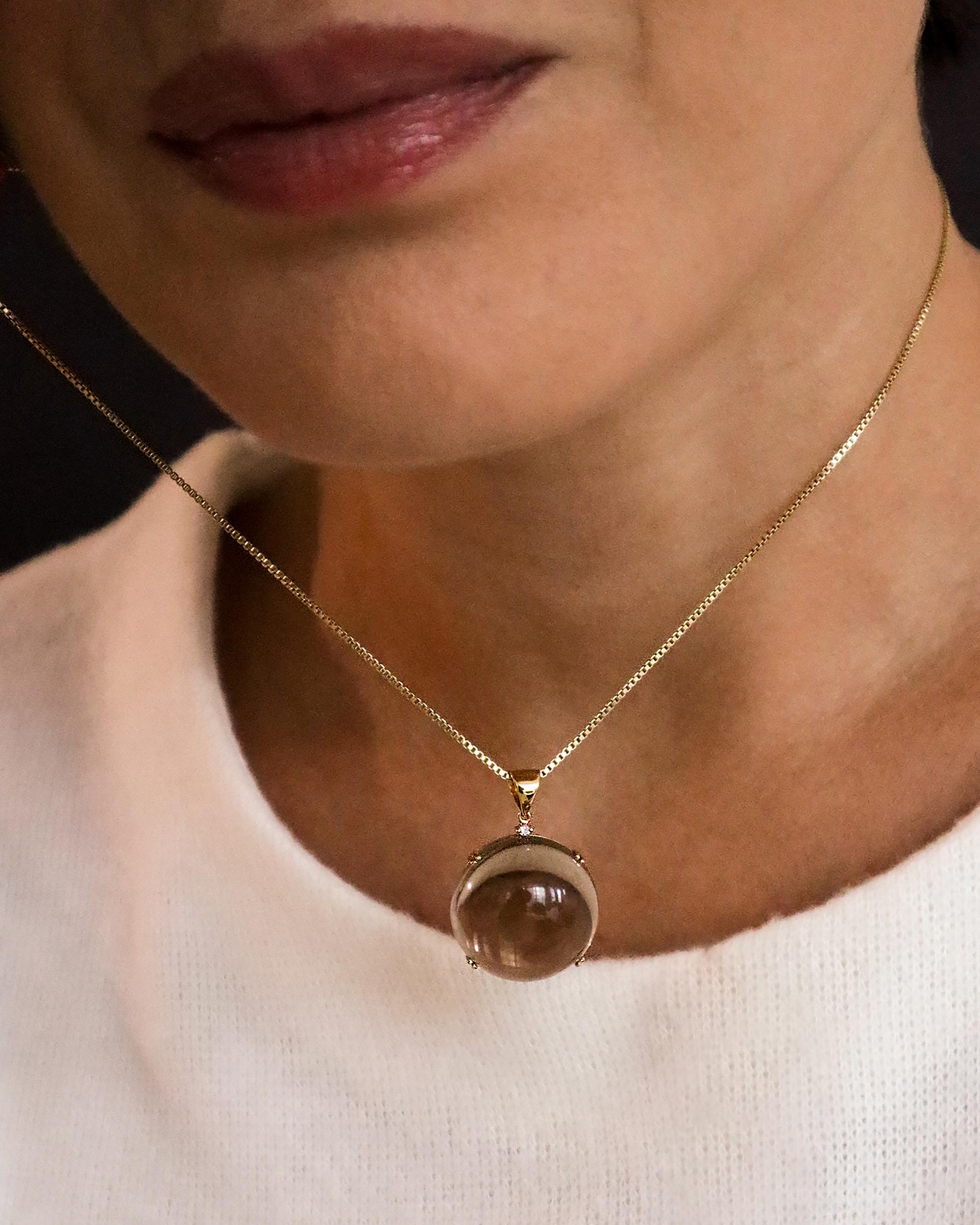 A simple and elegant round pendant featuring a stunning smoky quartz gemstone and a diamond.

Compatible with most chains.

Materials:

- 18k solid gold pendant

- 1 diamond of 1.5mm G color, VS-2 clarity

- 1 natural Brazilian smoky quartz round