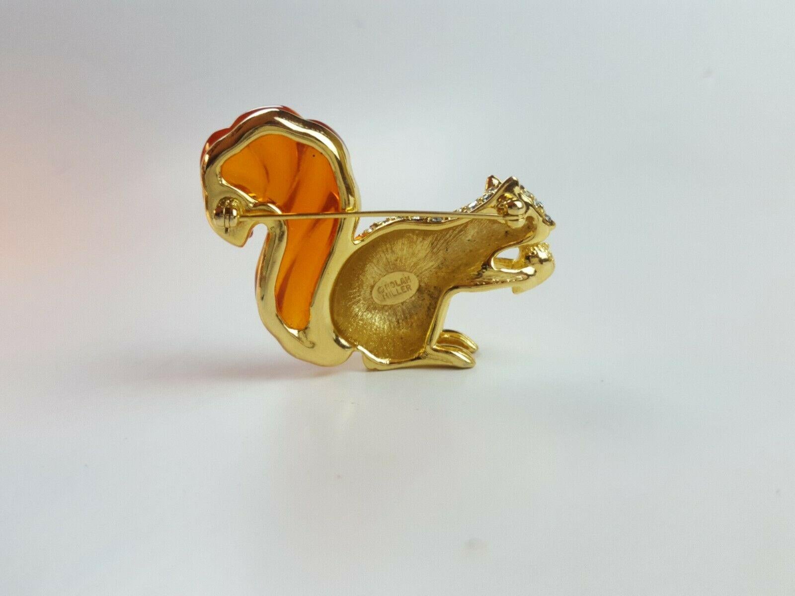 Vintage Brooch featuring a Squirrel holding an Acorn set with sparkling Rhinestones and displaying a Beautiful Amber Color Lucite Tail; Gold plate mounting; glass beads; Signed NOLAN MILLER. 