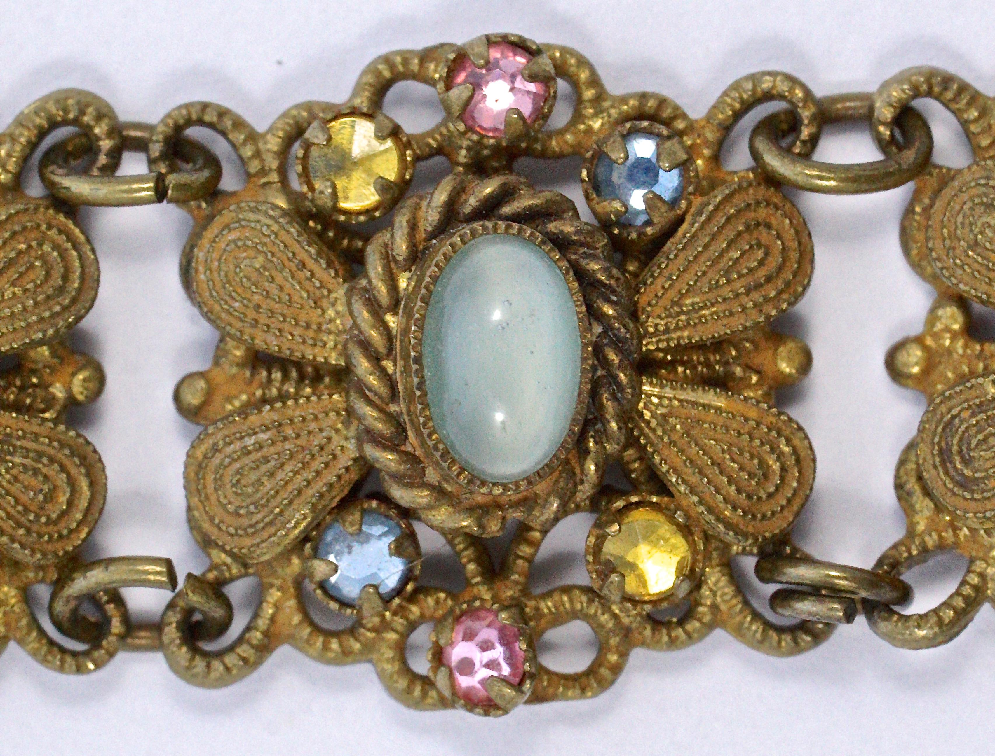 
Czech gold tone filigree detail link bracelet, featuring pale aqua moonglow cabochons in rope twist settings, and blue, pink and golden rhinestones. Measuring 16.5cm / 6.49 inches by 1.6cm / .63 inches, this vintage bracelet will fit a small wrist.