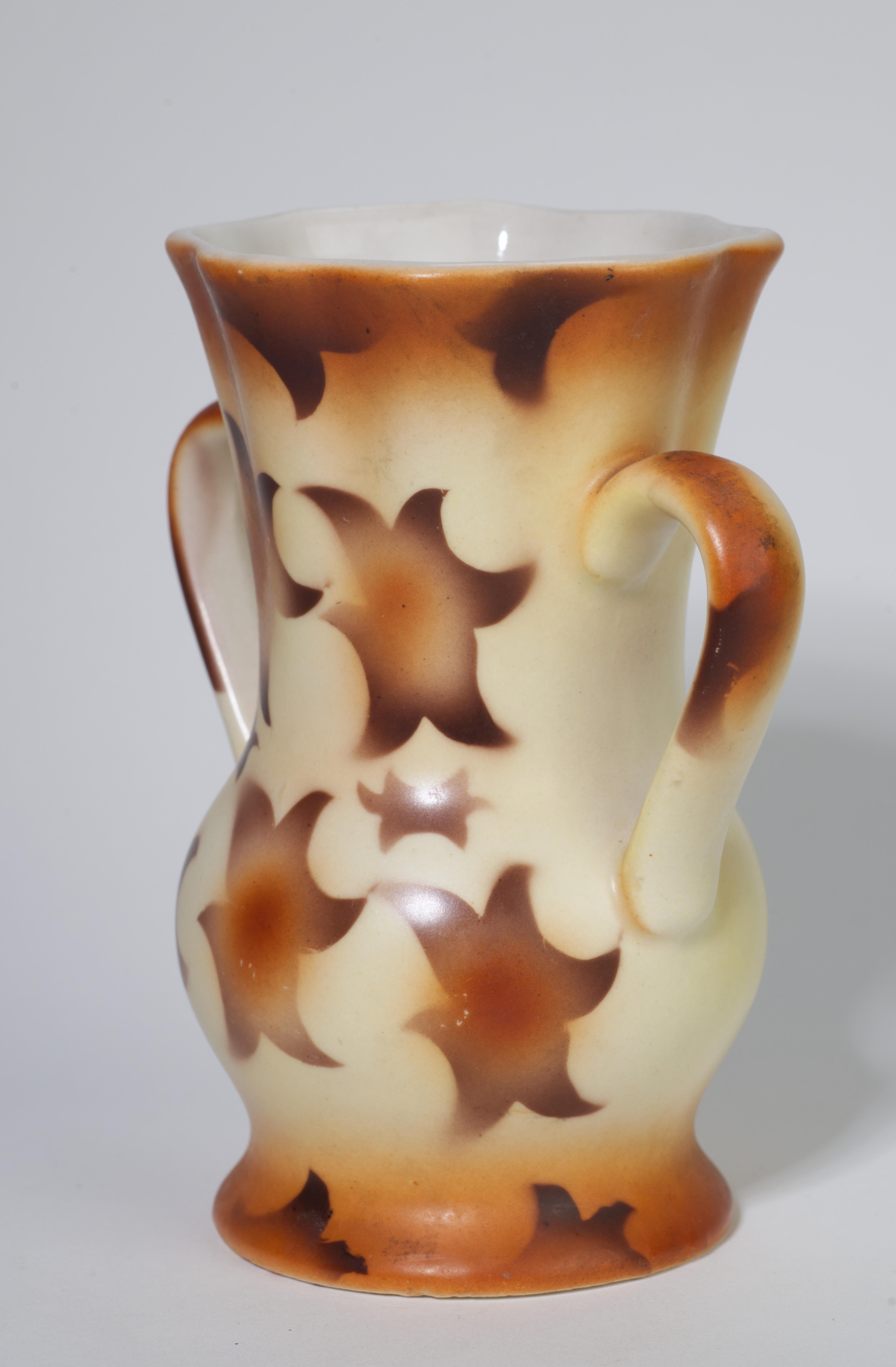 Ce rare vase en céramique avec poignées est décoré d'un décor géométrique abstrait composé d'étoiles brun chocolat et orange brûlé flottant sur un fond beige crème. Les poignées, le bord et la base sont accentués par des bandes de couleur orange