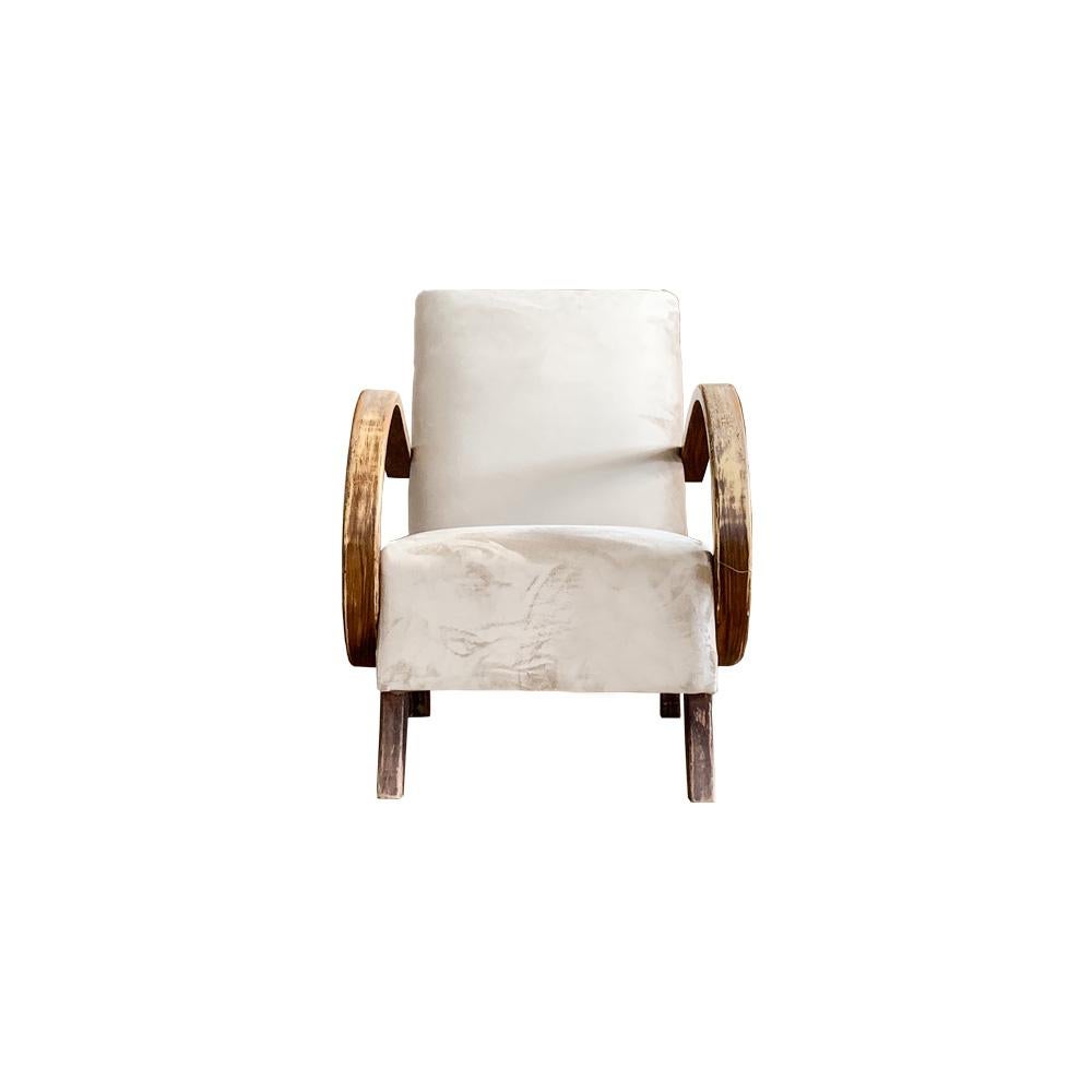 Diseñado entre 1950 y 1959, este sillón de mediados de siglo tiene los brazos de madera curvada con una pátina muy desgastada, propia de las piezas verdaderamente vintage. Tapicería clásica de terciopelo vintage en un cálido color crema.