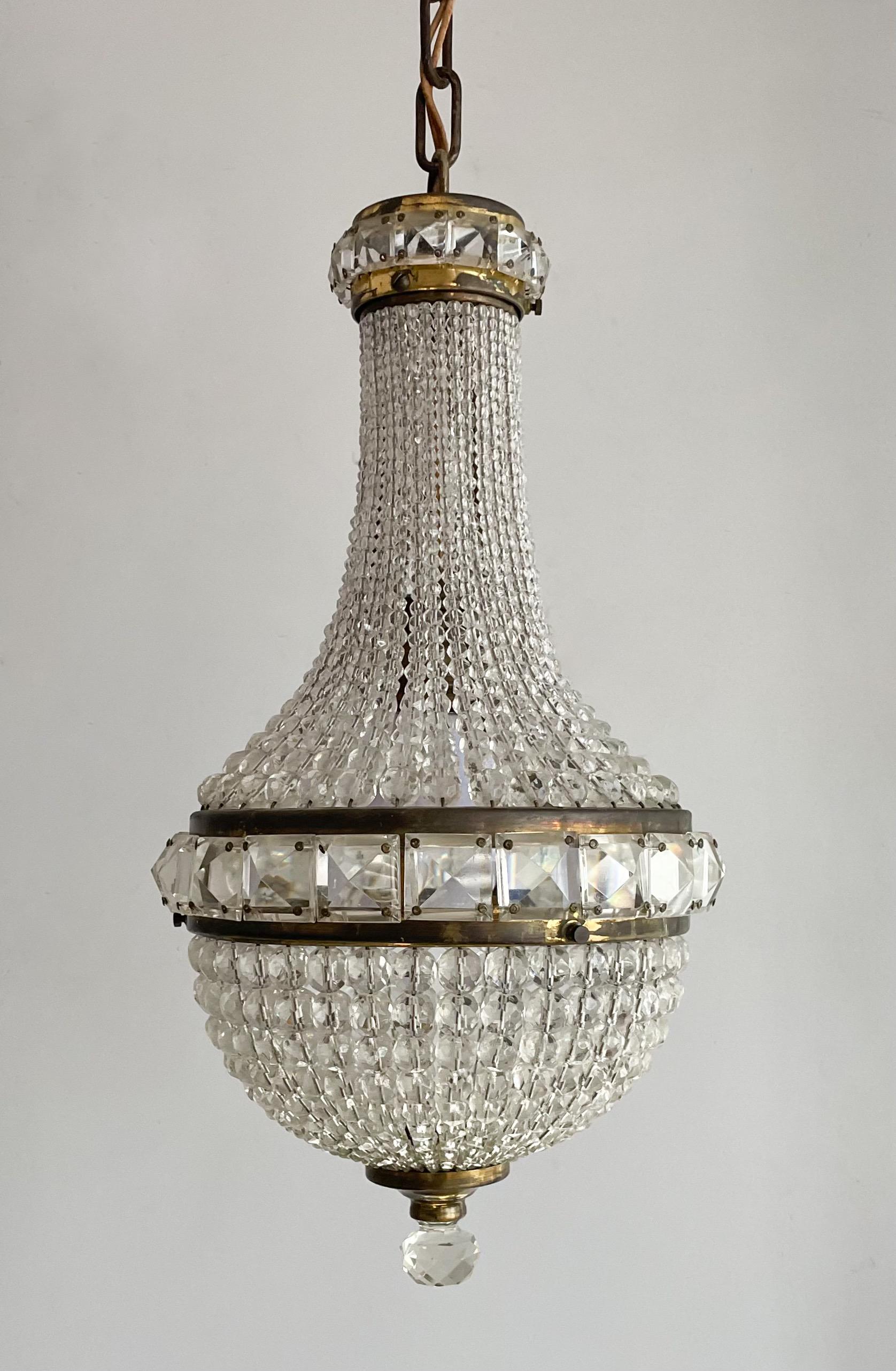 Gorgeous, Czech 1920s crystal beaded pendant chandelier in the neoclassical style.

The fixture consists of graduating glass beads secured by two brass, jeweled rings and a brass plate holding a faceted crystal ball at the bottom.

The chandelier is