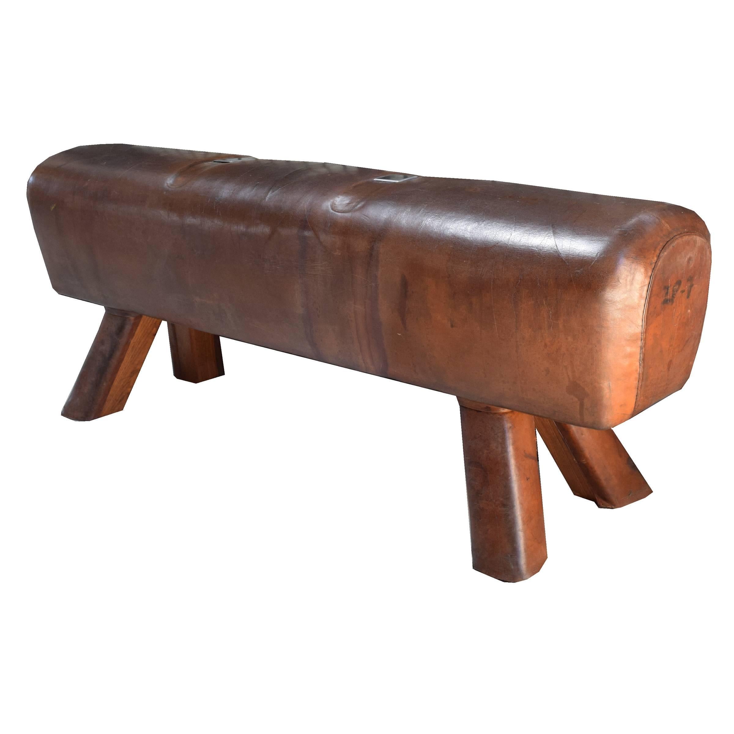 A fantastic early 20th century Czech leather pommel horse bench with leather covered wooden legs and custom steel plates covering the location of the original handles.