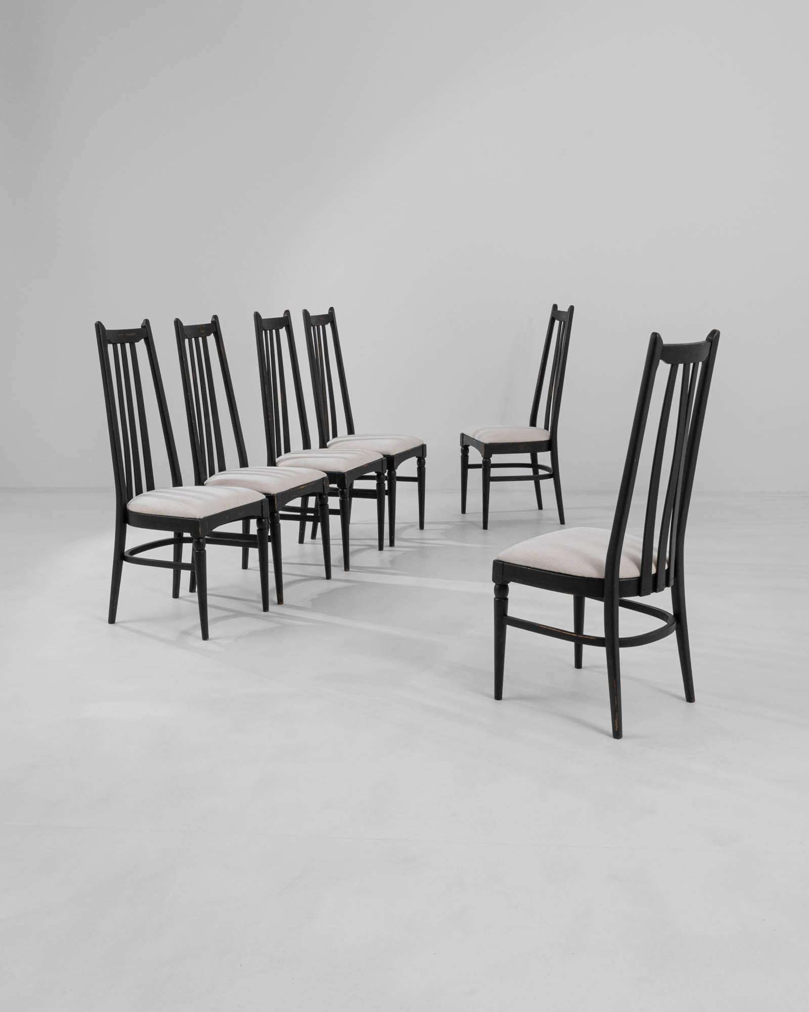 This set of six dining chairs, produced circa 1960 in Czechia, exudes a hint of gothic allure combined with mid-century modern style. The tall black backs, topped with minimalist finials resembling ears, and the sleek tapered legs, adorned with