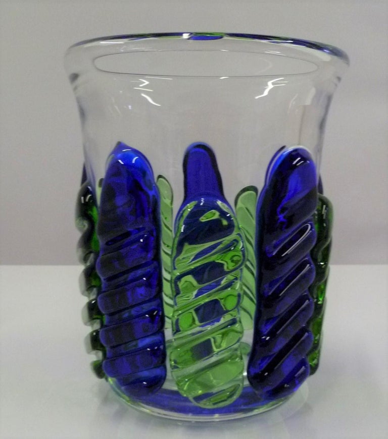 The sculptor and glass designer Ježek Pavel (1938 - 1999, Czechoslovakia) created this Modern and elegant lead glass vase in 1975 for Škrdlovice. The heavy glass vessel is crystal clear with applied sculpted leaves in alternating cobalt blue and