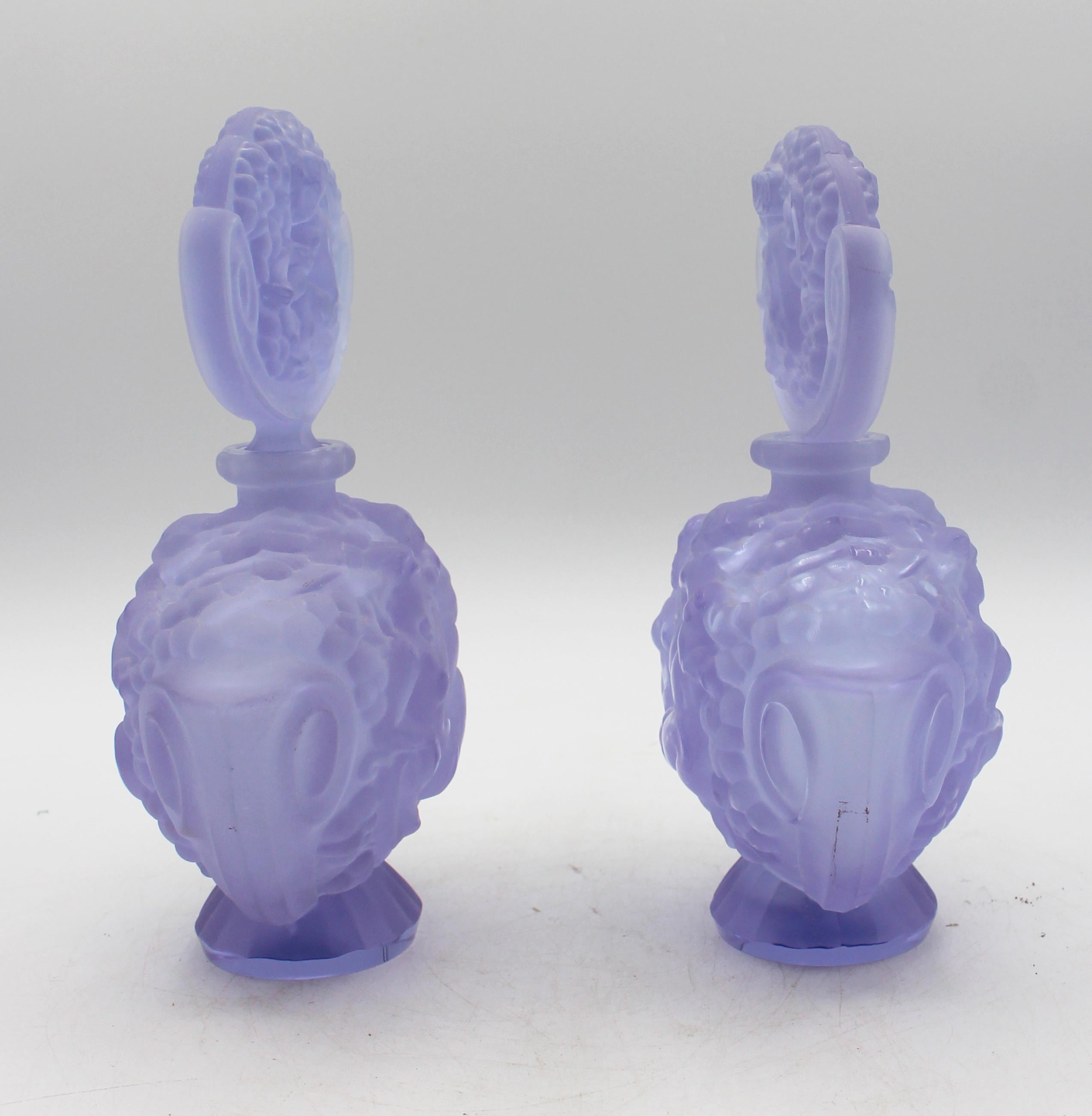 Pair of Art Deco period light violet frosted glass perfume bottles & stoppers, Czech. The bottles with recumbant female nudes & stoppers with putti. Design of Rudolf Hlousek. Some chips to each stopper (one with a more extensive chip). Labels