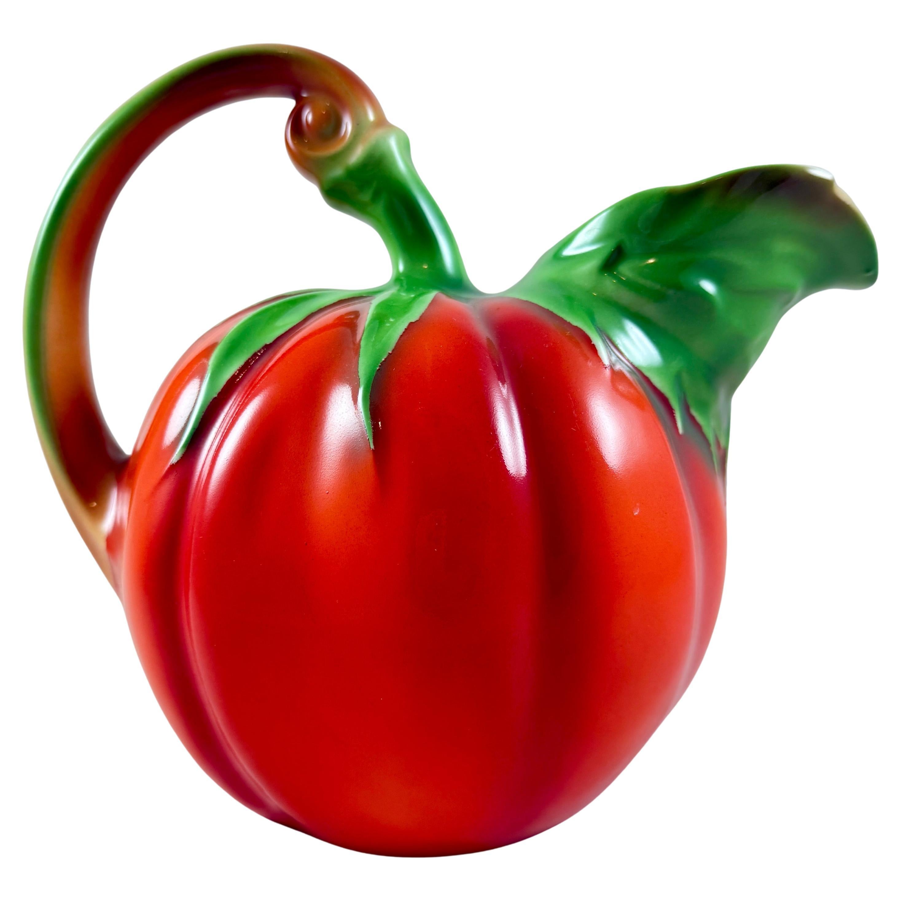 A bright red porcelain tomato pitcher, made in Czechoslovakia, circa 1920-1930.

A large pitcher holding 2 liters, realistically molded in the Art Nouveau style.
A branch-form handle curls into a top stem of green leaves. The green leaves also form
