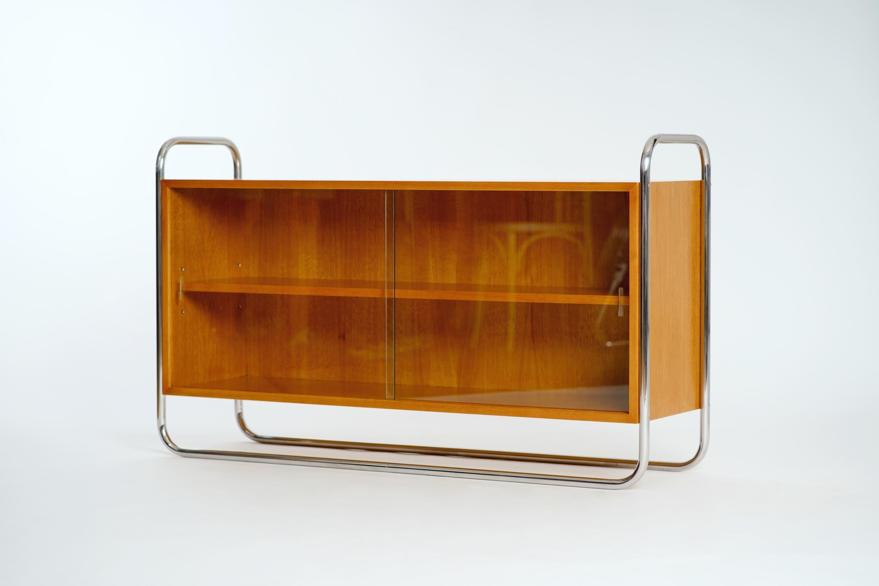 This light oak sideboard with glass sliding doors in a tubular steel frame was manufactured by UP Závody in the 1950s. 
Completely restored.