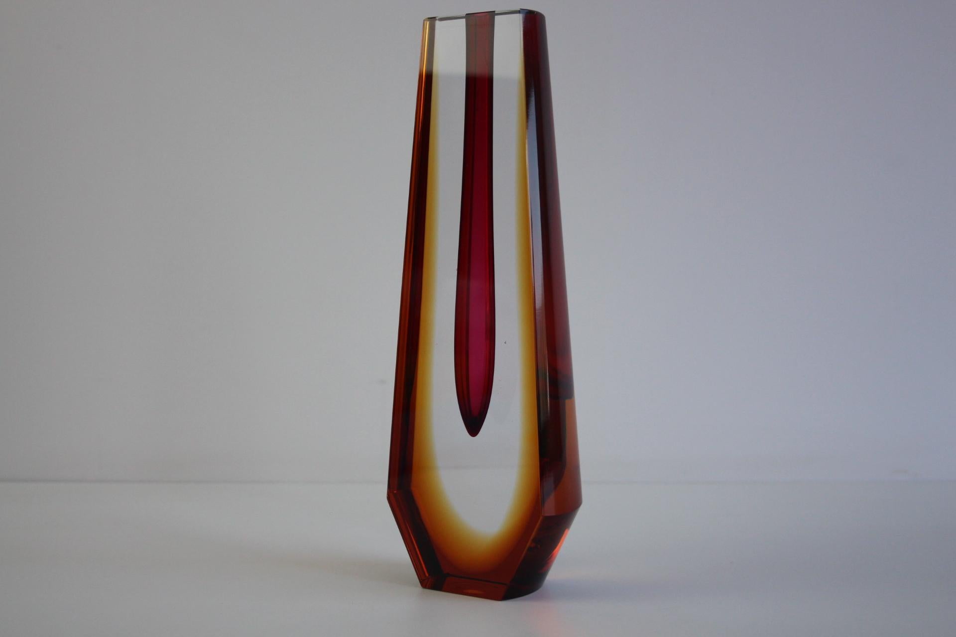Refinado jarrón checo de vidrio artístico sommerso, atribuido al renombrado diseñador Pavel Hlava, producido en Checoslovaquia en la década de 1960. Este elegante jarrón geométrico presenta una llamativa gota interior de color rojo rubí envuelta en