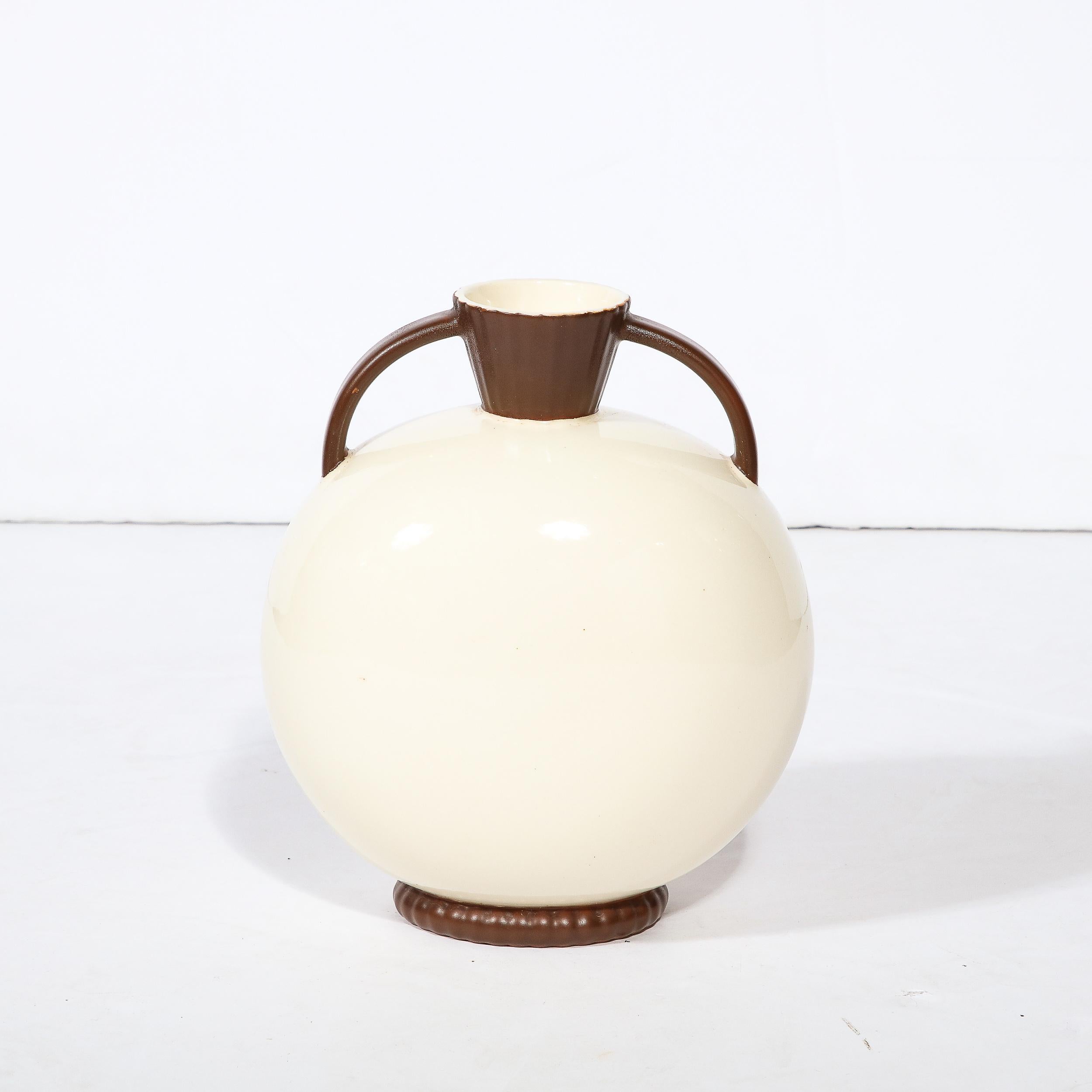 This elegant Art Deco ceramic vase was realized by the esteemed atelier of Royal Crown in Czechoslovakia circa 1930. Suggesting a modern interpretation of the classic Greek amphora vase, the piece offers a rotund spherical body sitting on an banded