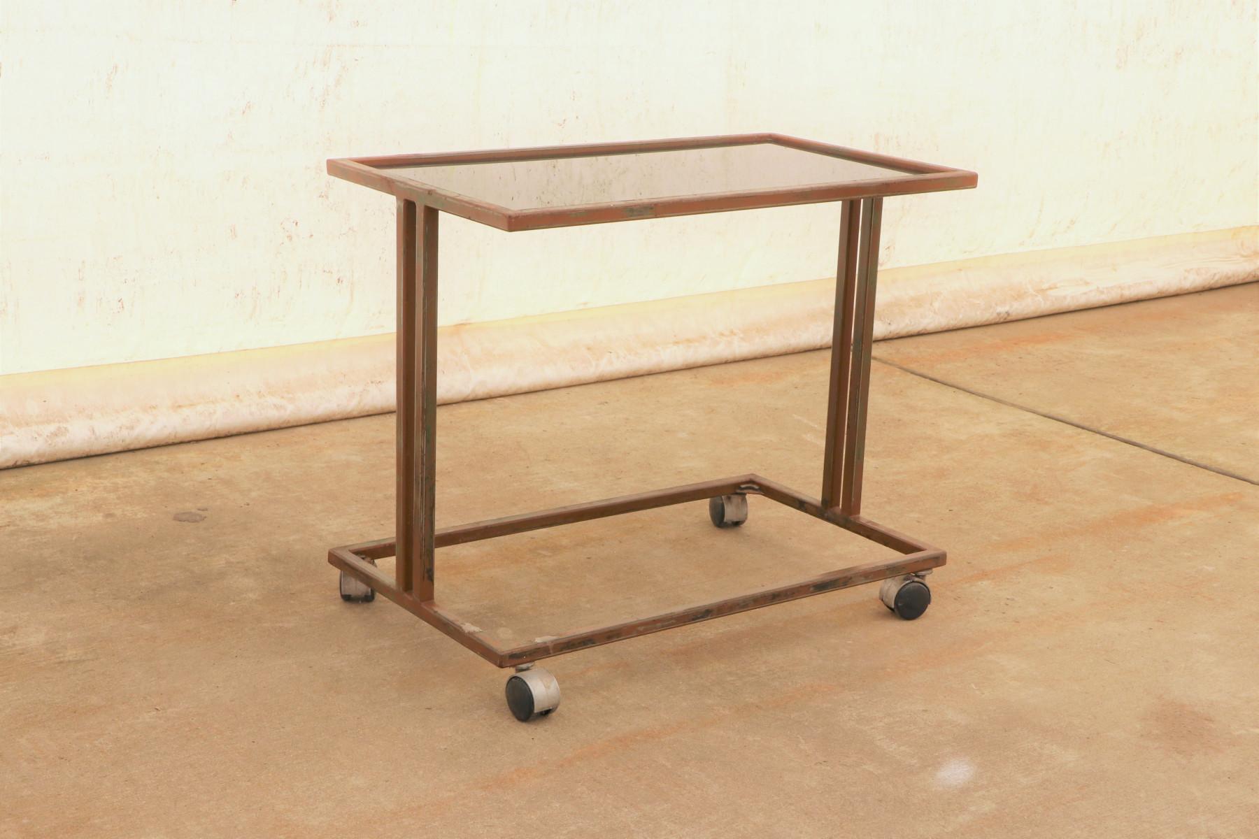 This Industrial-style serving trolley on wheels was made in the former Czechoslovakia in the 1970s.
It features an iron structure and a glass top. The table is in good preserved condition.
Signs of time and wear create an interesting and engaging