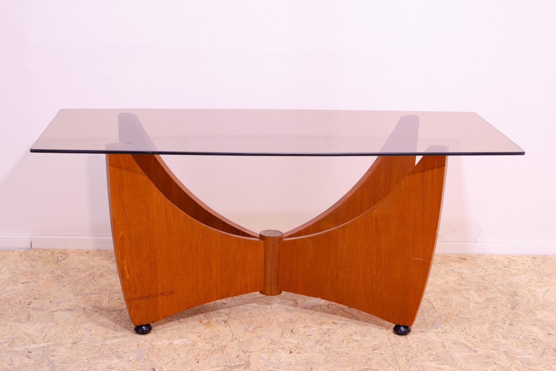 Cette table basse a été fabriquée dans l'ancienne Tchécoslovaquie dans les années 1980 pour faire partie d'un salon.
Son design est élégant et moderne.

Il possède des pieds de forme intéressante avec des découpes arquées et un plateau en verre