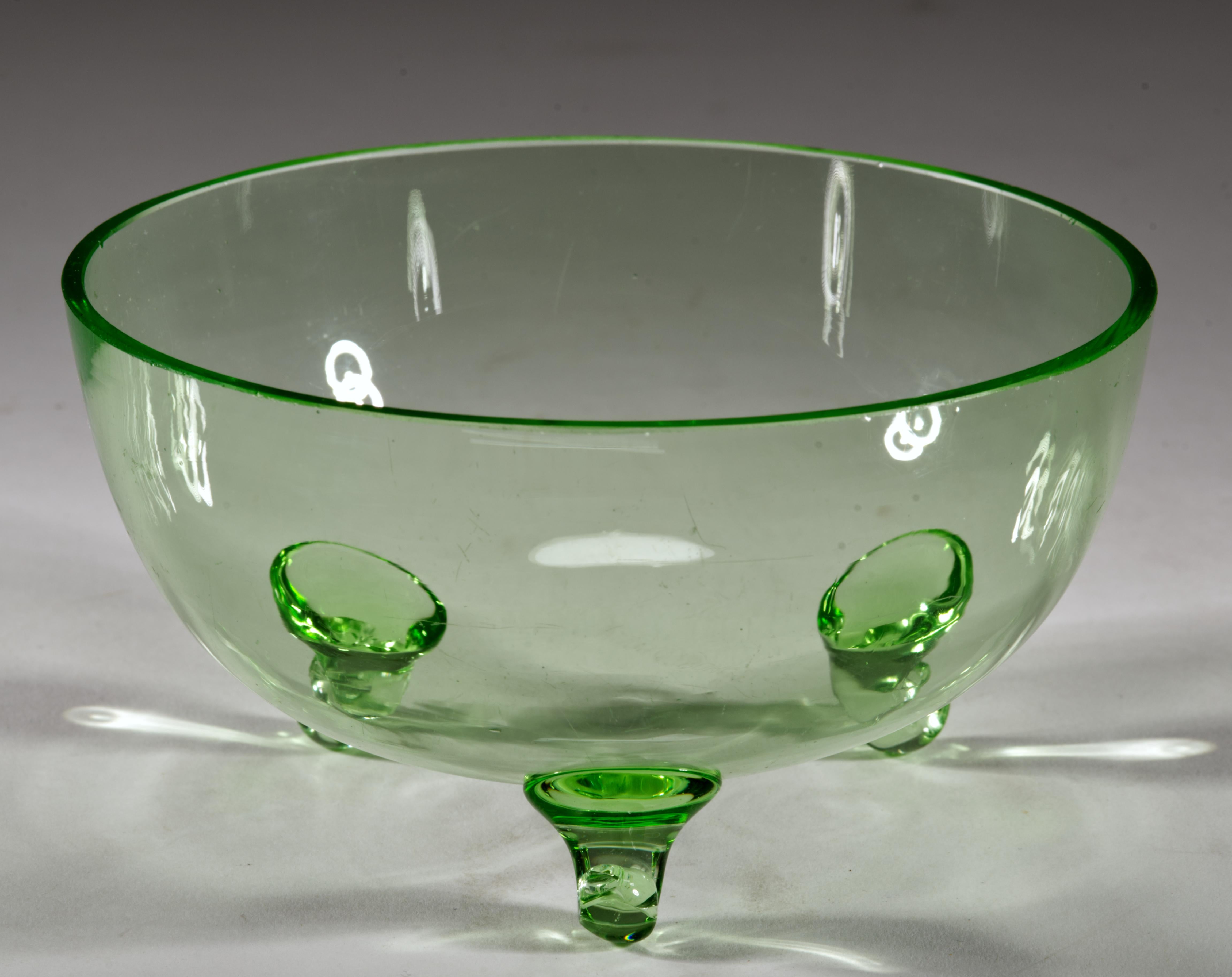  L'elegante ciotola vintage in vetro verde uranio presenta una forma minimale e arrotondata con 3 piedini curvi. La forma aerodinamica Art Decor e la tavolozza monocromatica della ciotola le permettono di essere utilizzata sia come decorazione da