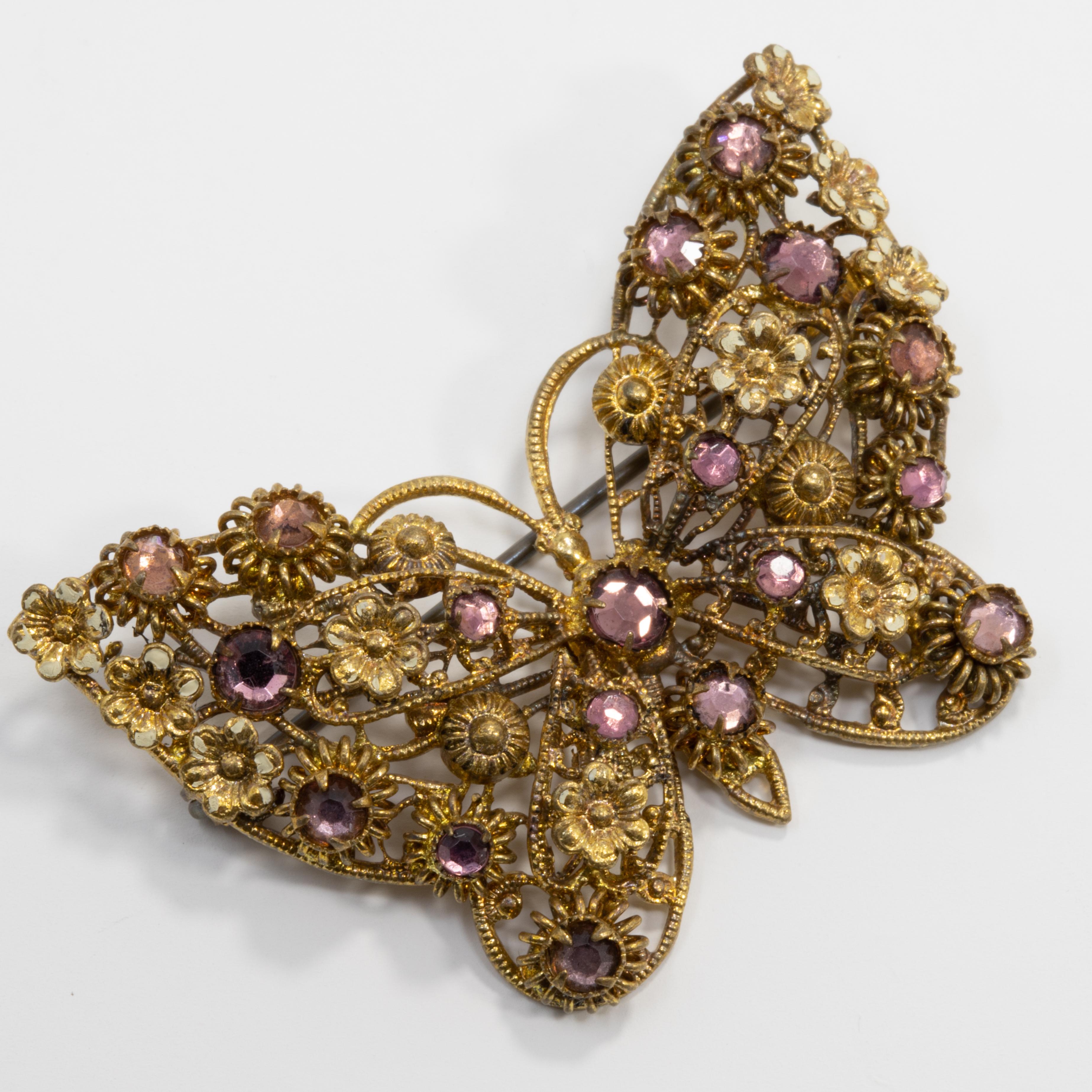 An exquisitely detailed vintage butterfly brooch. Features intricately detailed wings and body accented with enameled flowers and amethyst-colored crystals. Gilt brass metal.

Some discoloration and wear of flower enamel, only noticeable upon close