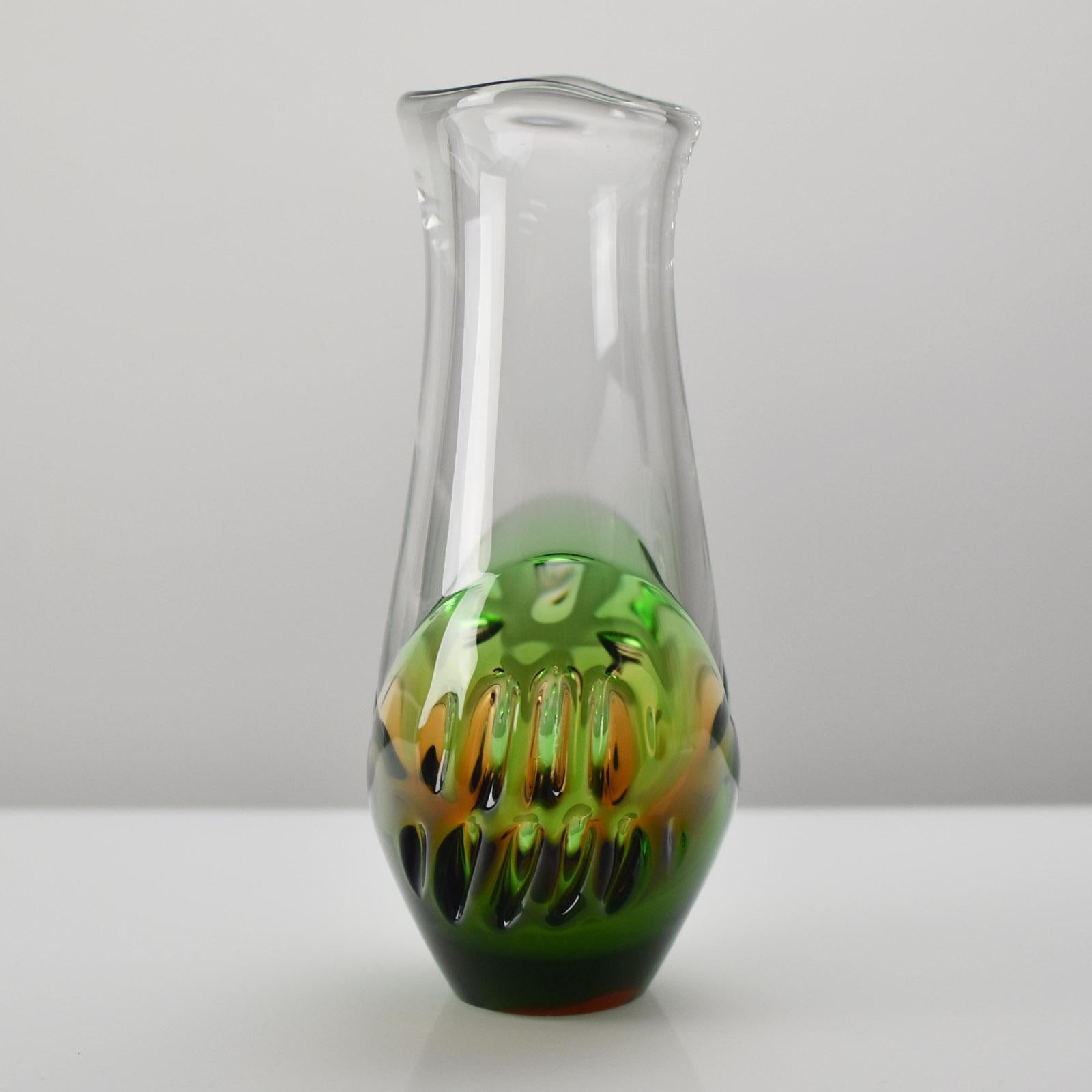 Questo straordinario vaso vintage in vetro artistico di Skrdlovice, realizzato nel 1976 dal designer Ladislav Palacek, esemplifica la maestria dell'arte vetraria cecoslovacca della metà del secolo. Il pezzo presenta un corpo in vetro trasparente con