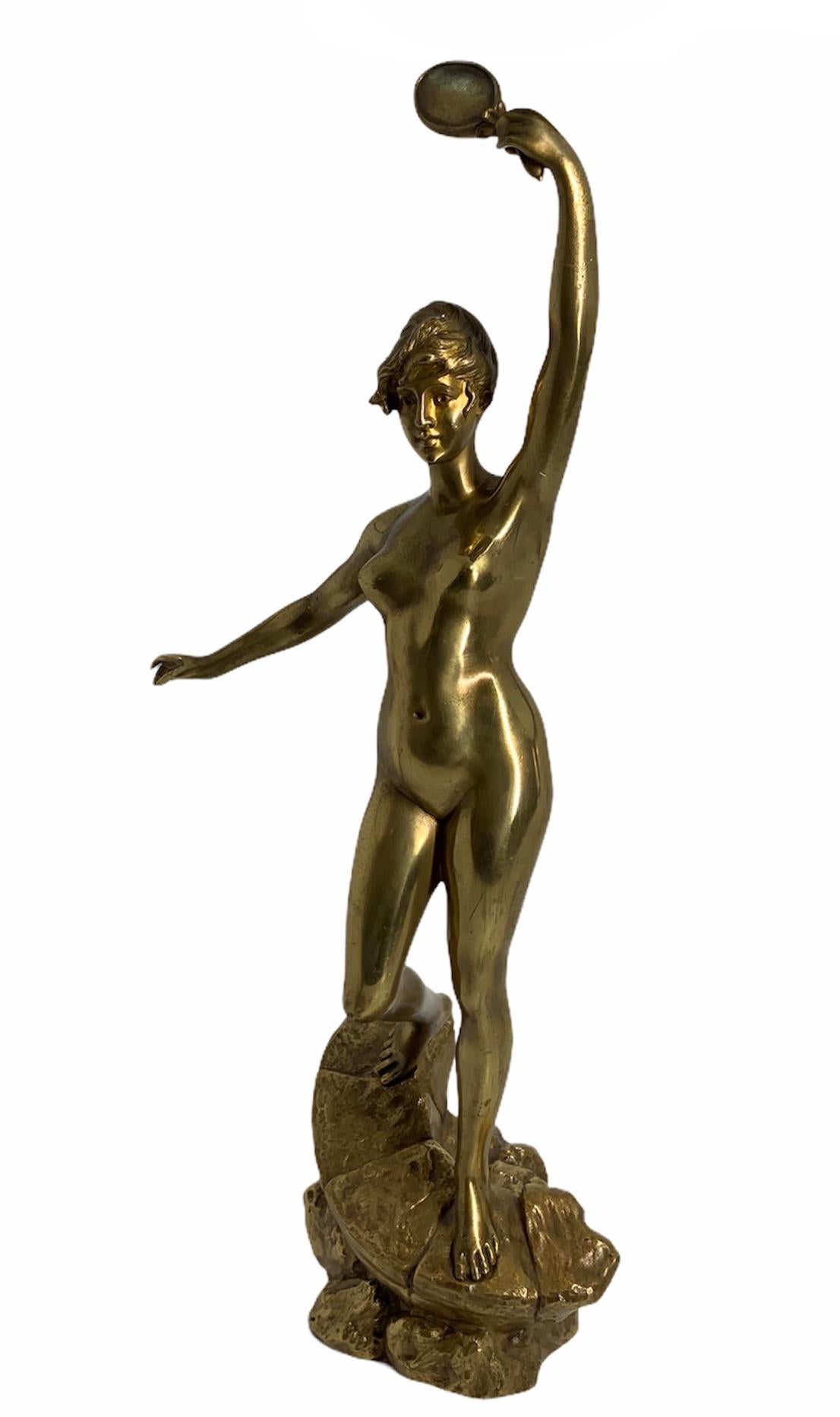 This is a gilt bronze sculpture of a happy nude lady. She is lifting her left arm/hand and holding a mirror while looking at herself in it. She is standing over a sloped shaped rock over another rock. The sculpture is signed by D.Grisard.