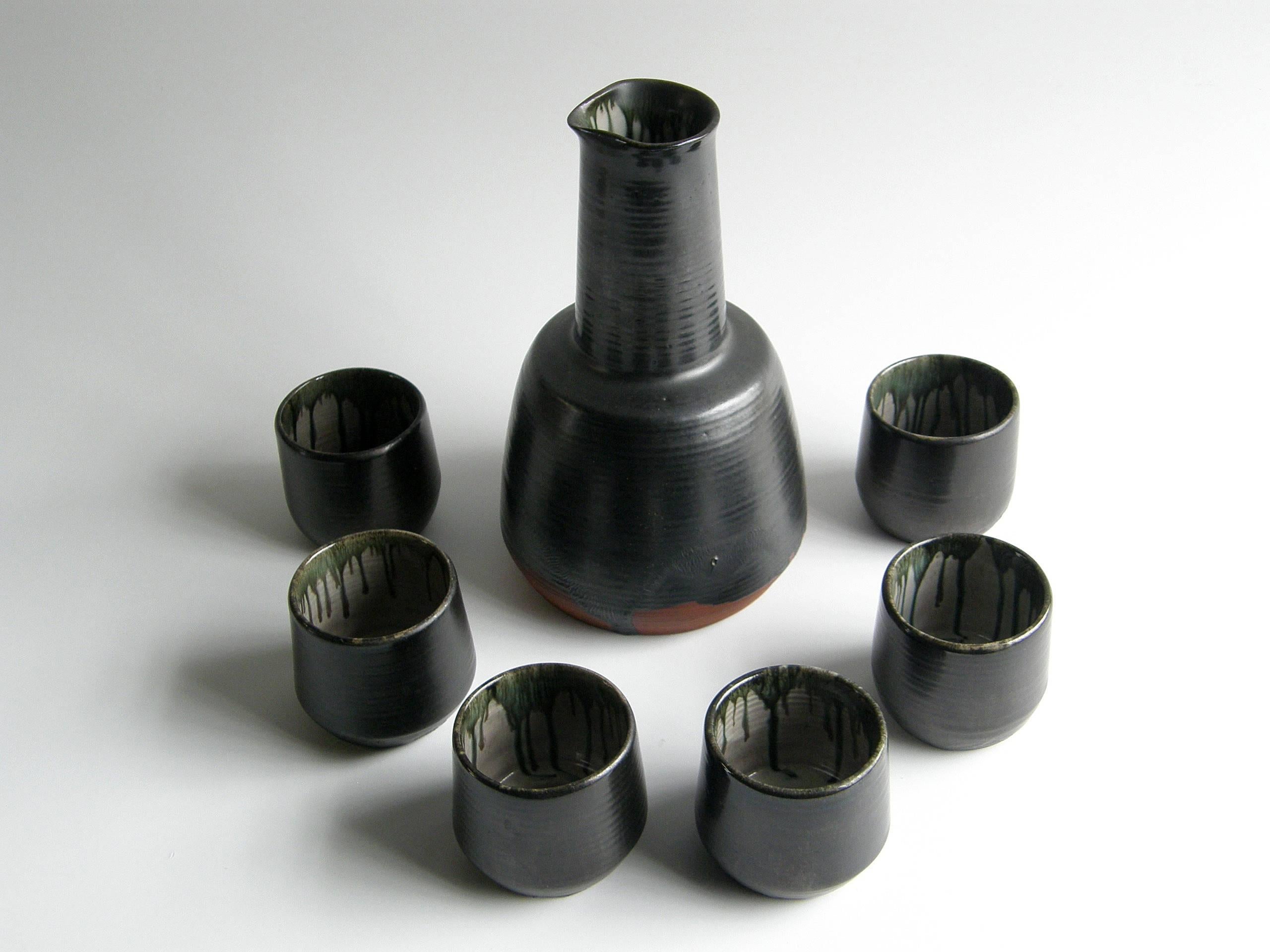 Cet ensemble de pichets et de tasses en céramique faits à la main présente des formes classiques et simples. Le traitement de la glaçure est merveilleusement irrégulier, embrassant la spontanéité du processus. La glaçure plus sombre de l'extérieur