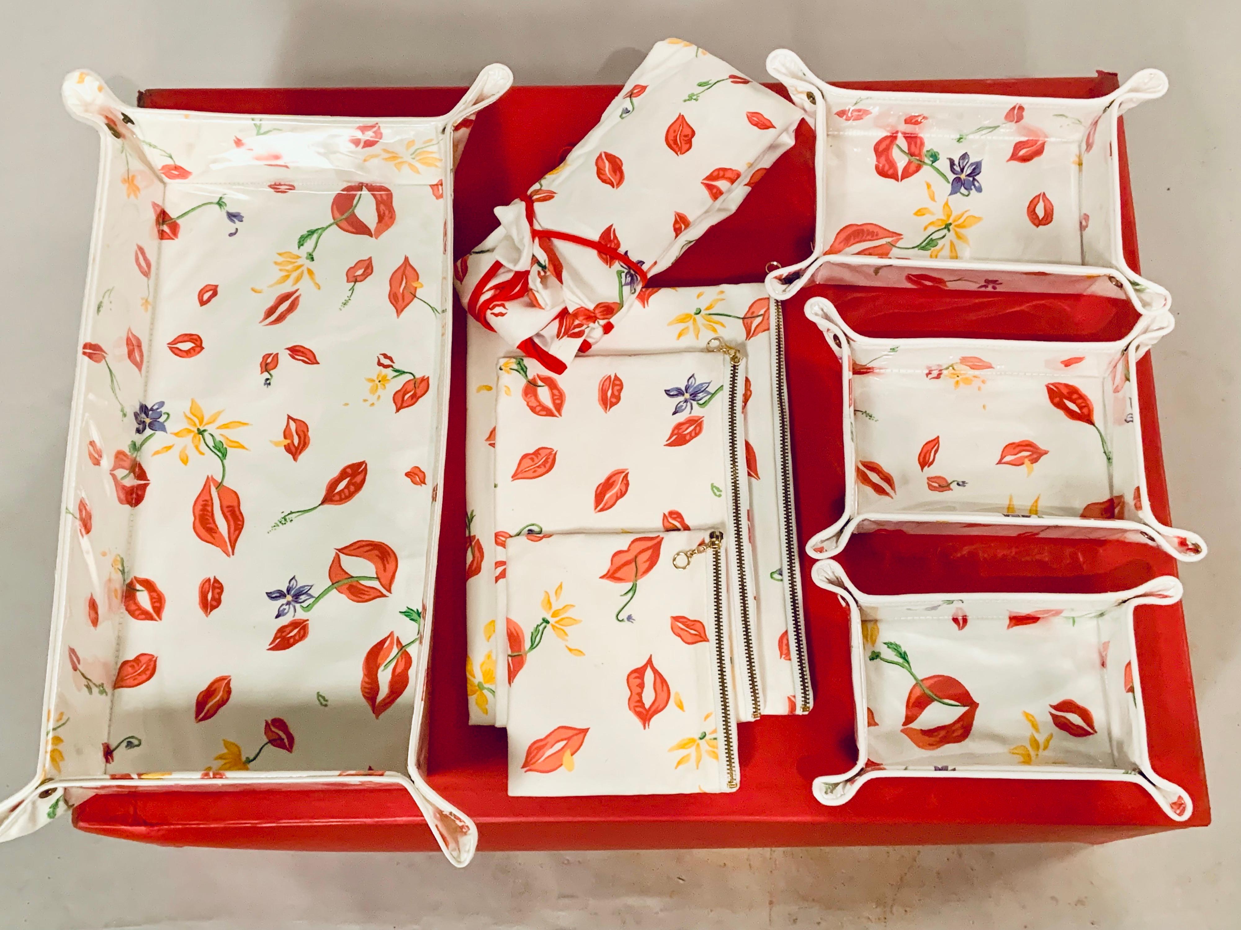 This eight piece group of D. Porthault Red Lips pattern travel accessories includes a large tray with a plastic cover, and a graduated set of three matching trays. All of these pieces snap together at the corners and then unsnap to pack flat in a